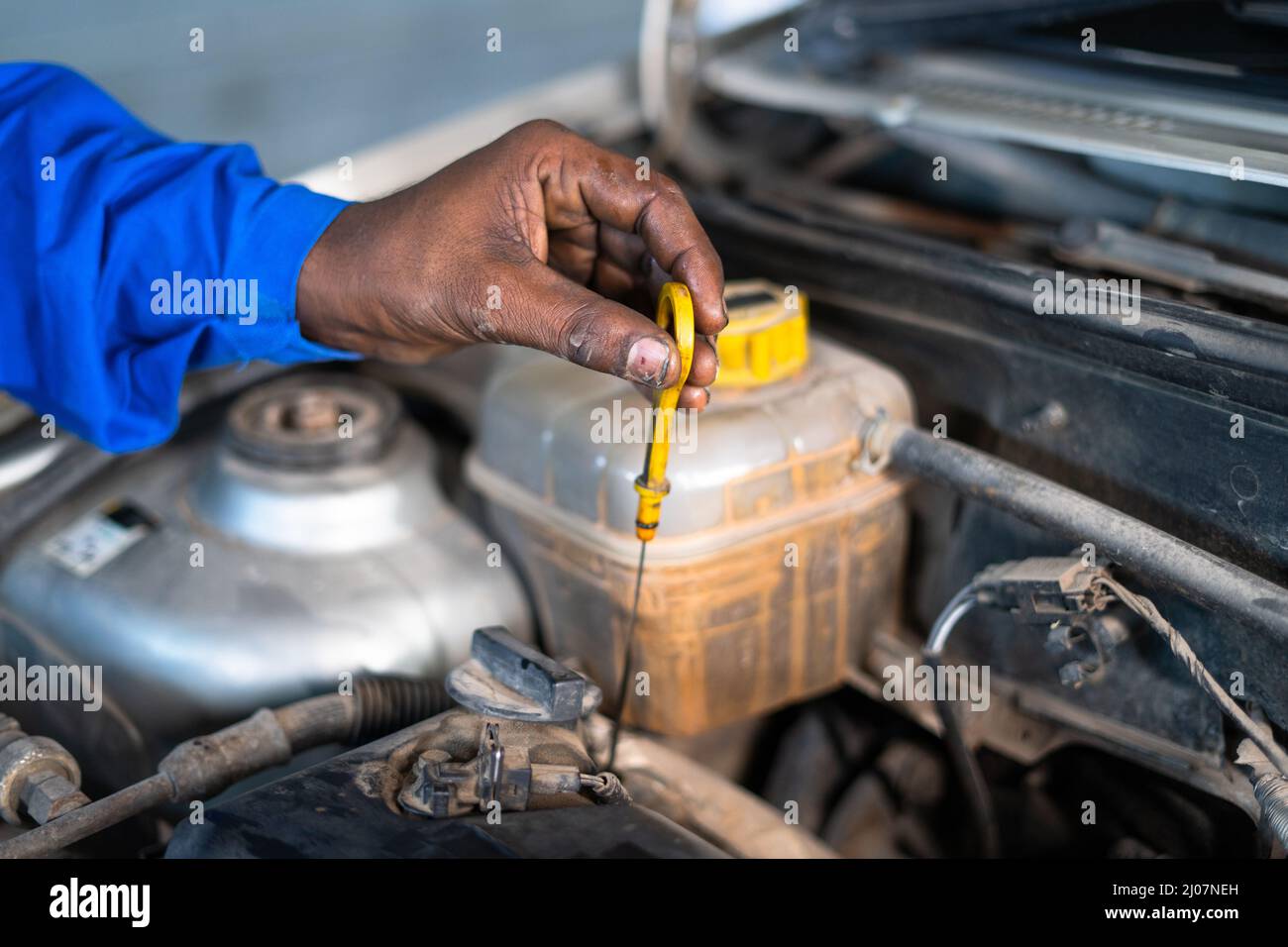 Nahaufnahme der Hände des Automechanikers, die den Motorölstand des Autos in der Garage prüfen - Konzept für Wartungsservice, Blaukragenarbeiten und Schmiermittel Stockfoto