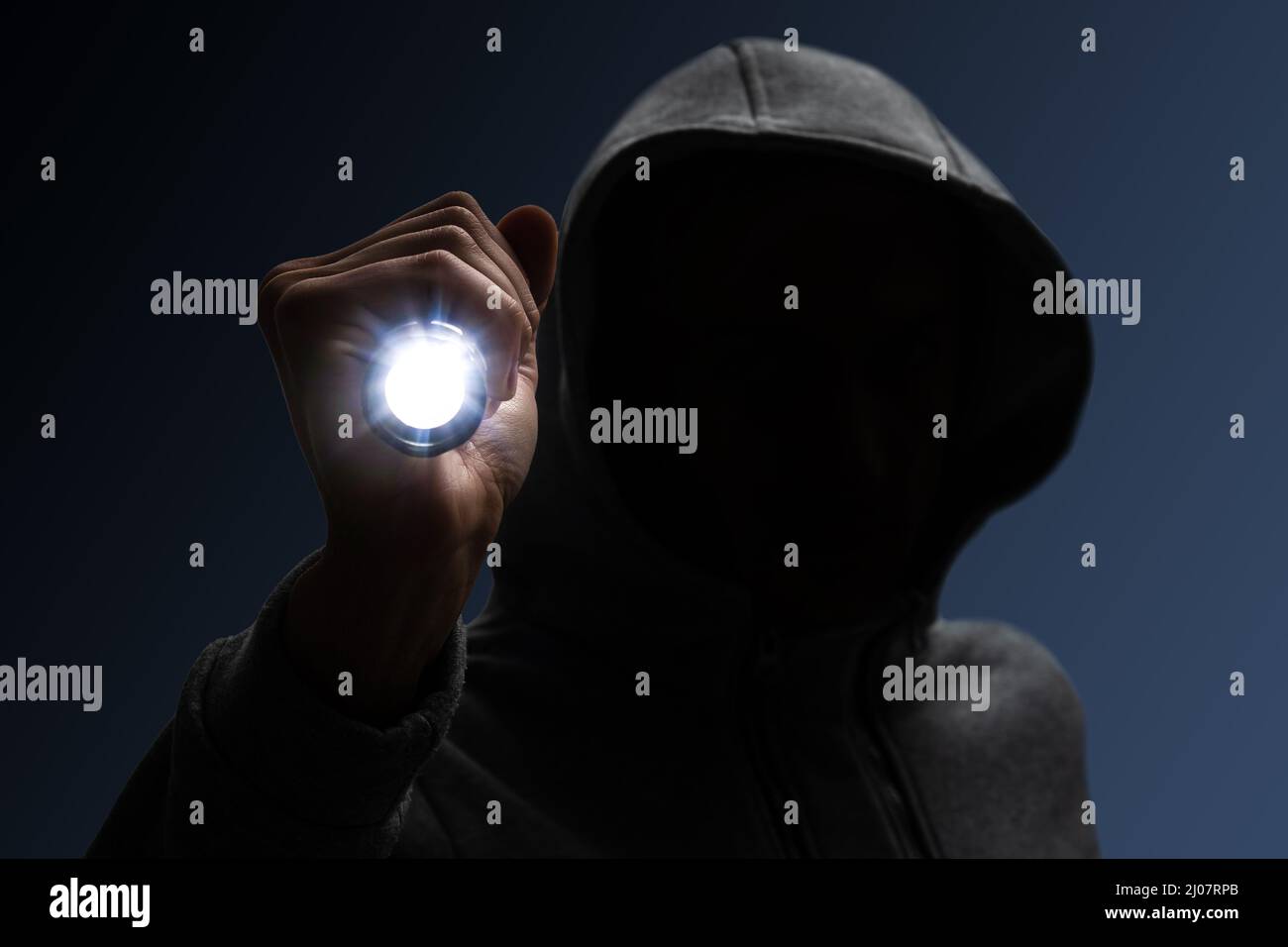 Einbrecher mit Kapuze. Silhouette von Dieb und Taschenlampe Stockfoto