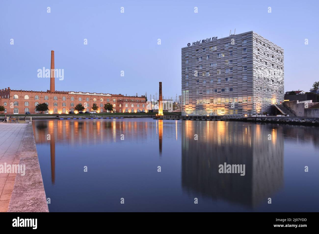 Das moderne Hotel Melia Ria und das Kongresszentrum (ehemaliges Fabrikgebäude) spiegeln sich in der Abenddämmerung im Canal do Cojo, Aveiro Portugal, wider. Stockfoto