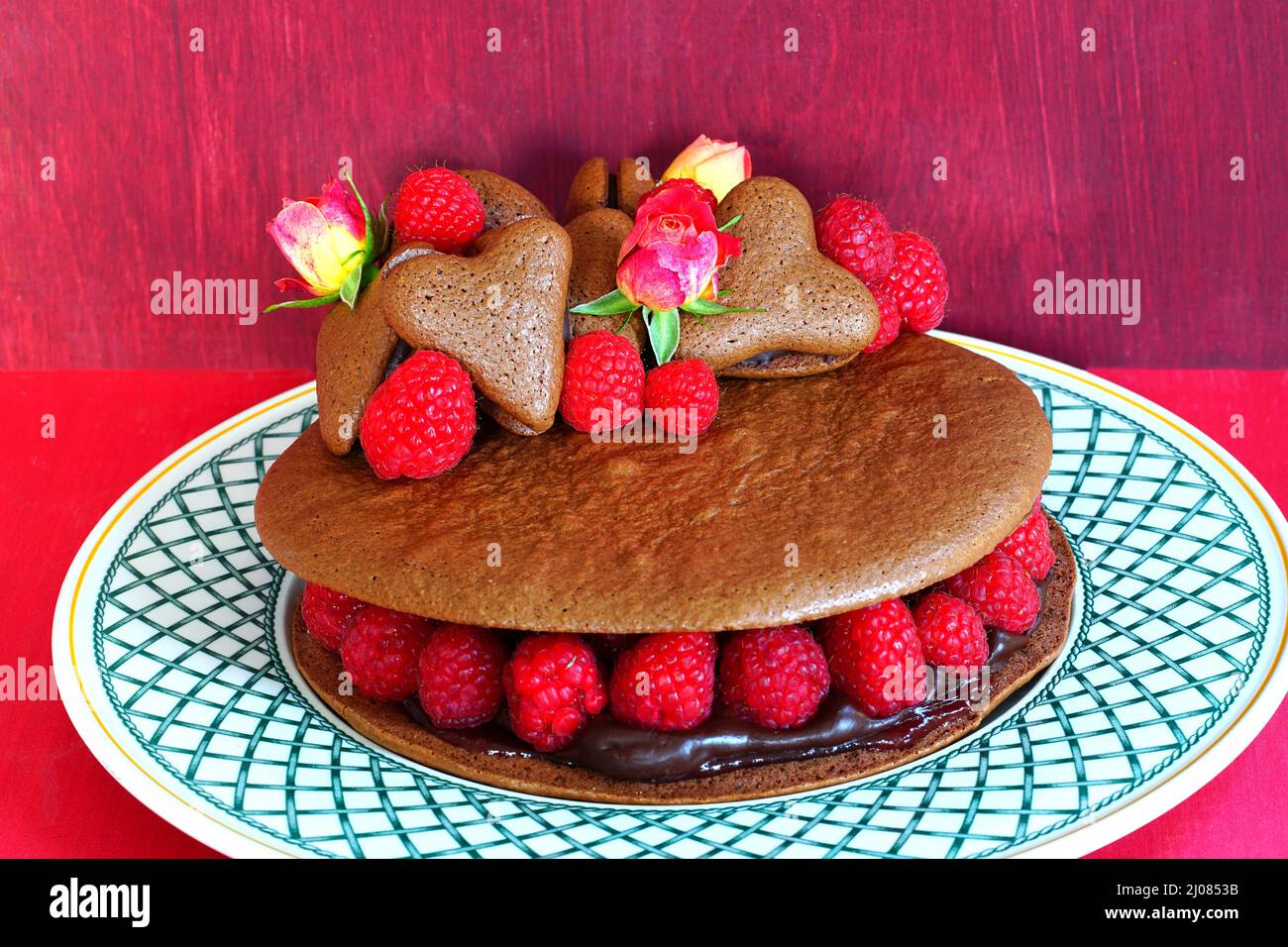 Ein riesiger Makkaronkuchen aus Schokolade mit frischen Himbeeren und Rosenblüten Stockfoto