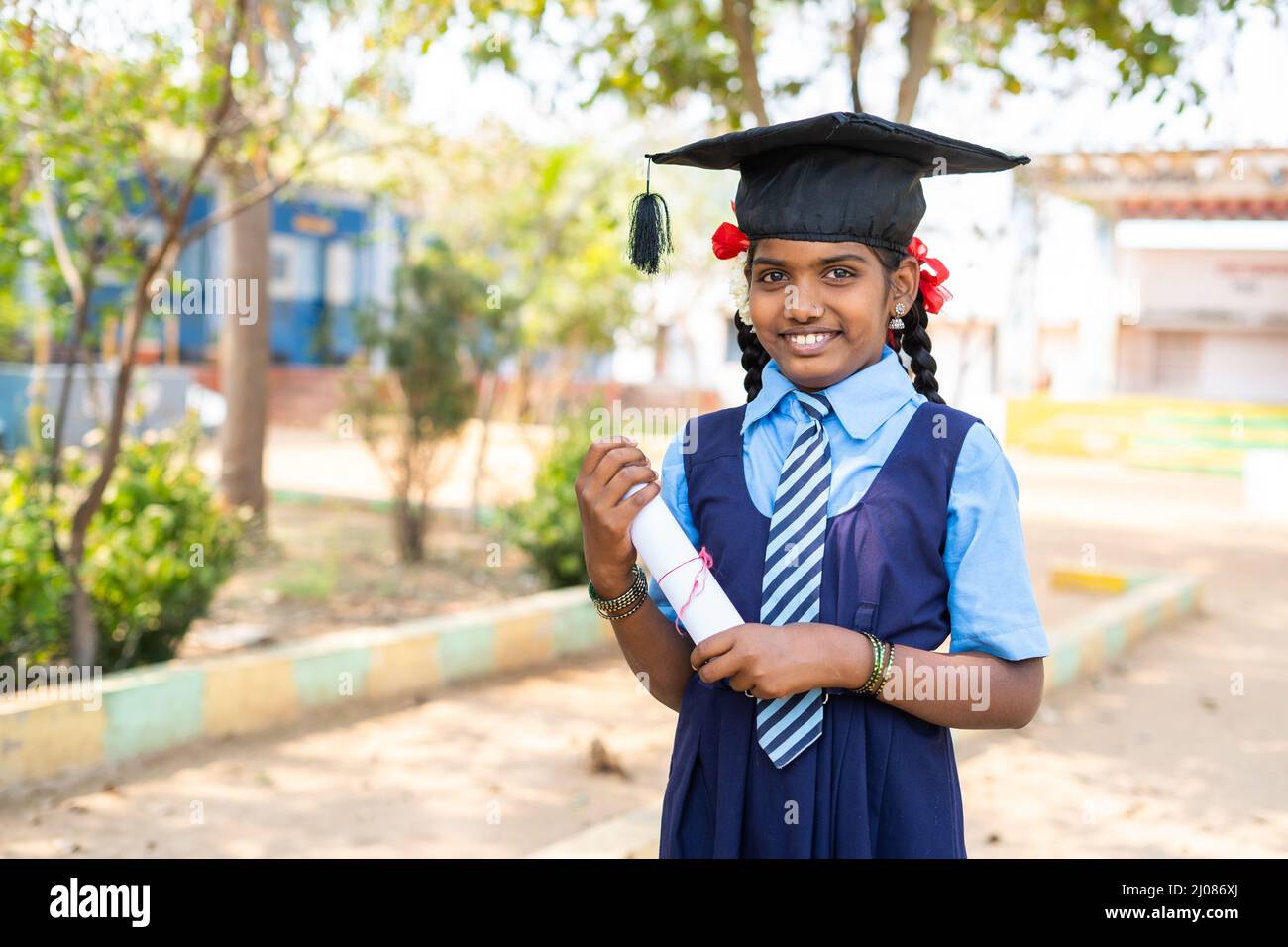 Glückliches Mädchen Kind in Uniform stehen, indem sie über den Abschluss träumen, während Abschlusszeugnis in der Schule - Konzept der zukünftigen Karriere, Bildung Stockfoto