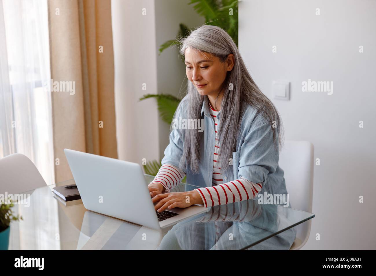 Frau, die zu Hause an einem tragbaren Laptop arbeitet Stockfoto