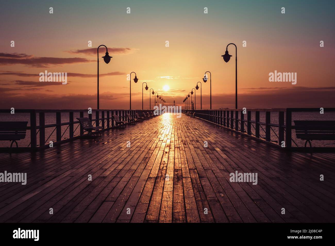 Wunderschöne Landschaft am Morgen am Meer. Hölzerner Pier mit einem bunten Himmel in Gdynia Orlowo, Polen. Stockfoto