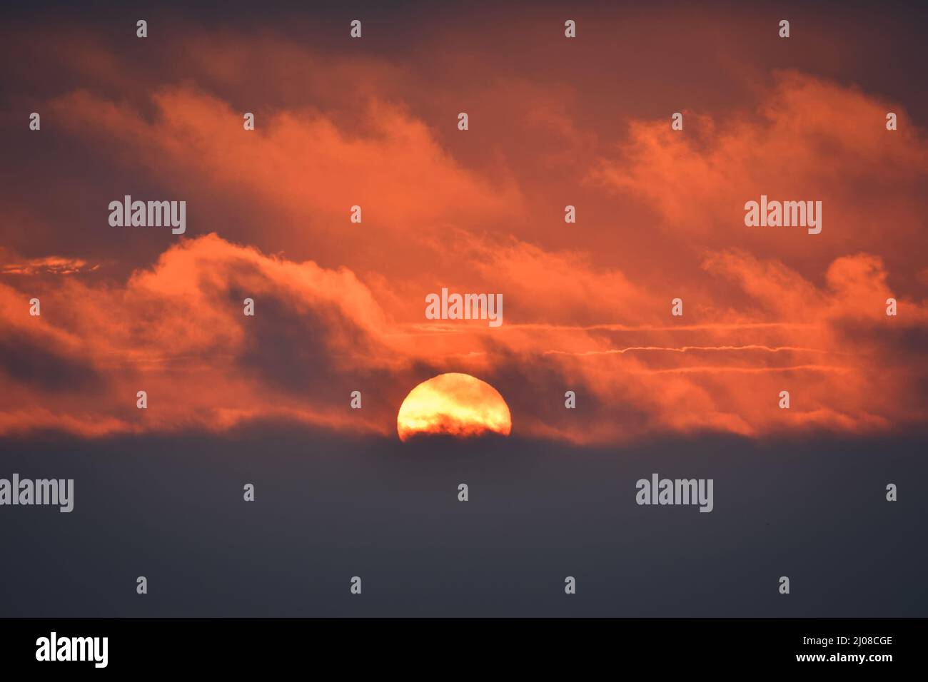 Schönes, farbenfrohes, abstraktes Stück Himmel. Gelbe Sonne auf einem Hintergrund von Wolken bei Sonnenuntergang. Stockfoto