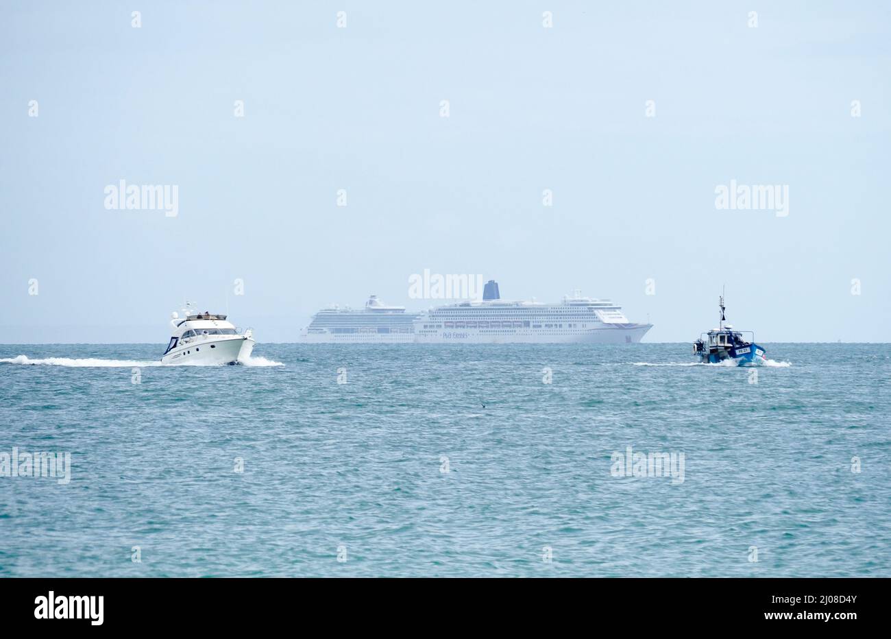 Zwei große Kreuzfahrtschiffe ankerten auf See mit einem Motorcruiser und einem kleinen Fischerboot im Vordergrund Stockfoto
