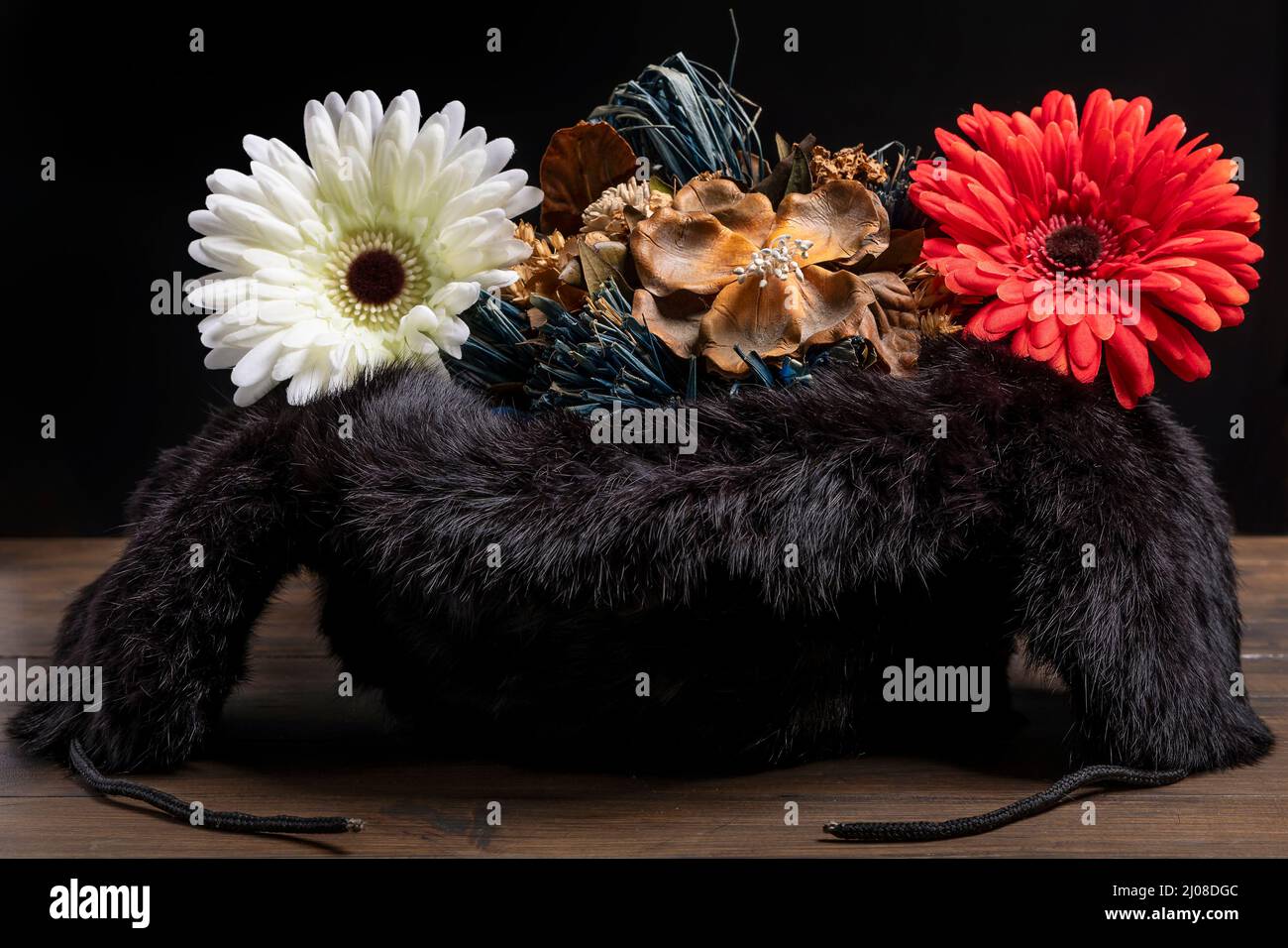 Ein umgekehrter russischer Uschanka-Hut enthält getrocknete, gefälschte Blumen als Symbol für Frieden und Liebe Stockfoto