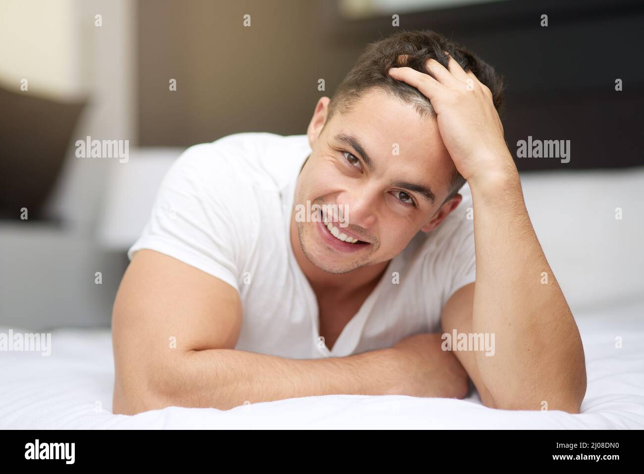Ich beginne meinen Tag gut. Kurzer Schuss eines hübschen jungen Mannes, der im Bett liegt. Stockfoto