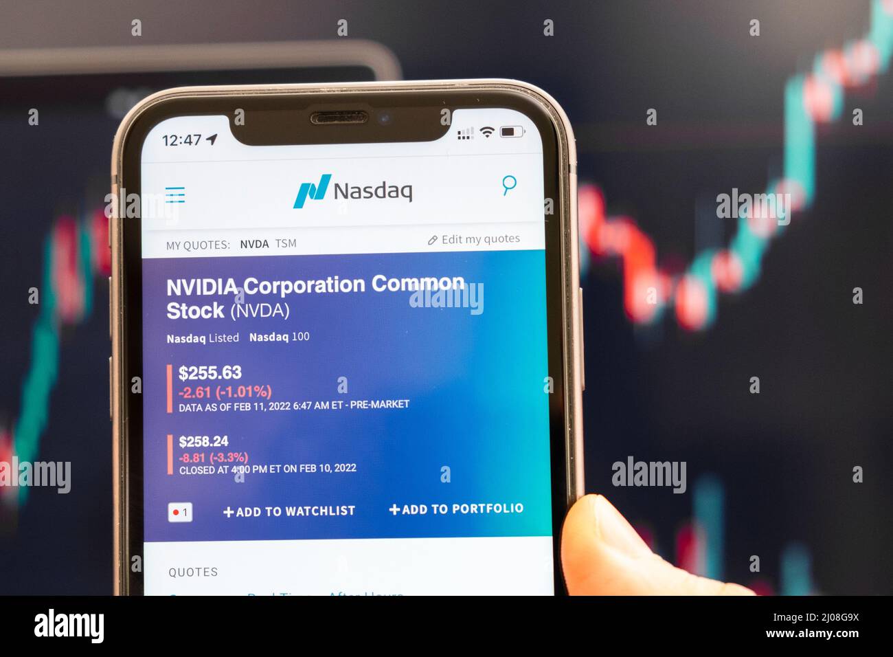 NVIDIA NVDA-Logo des Aktienkurses auf dem Bildschirm des Smartphones in mans Hand mit sich ändernden Trend auf dem Chart im Hintergrund, Februar 2022, San Francisco, USA. Stockfoto