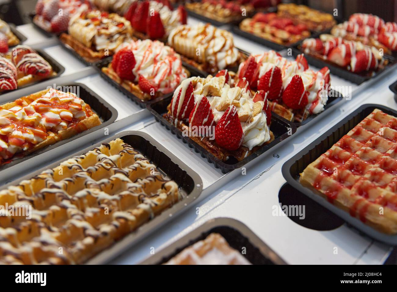 Verschiedene traditionelle belgische Waffeln mit Schokolade, Speculoos, Schlagsahne und Obst werden in einem Laden in Brüssel ausgestellt Stockfoto