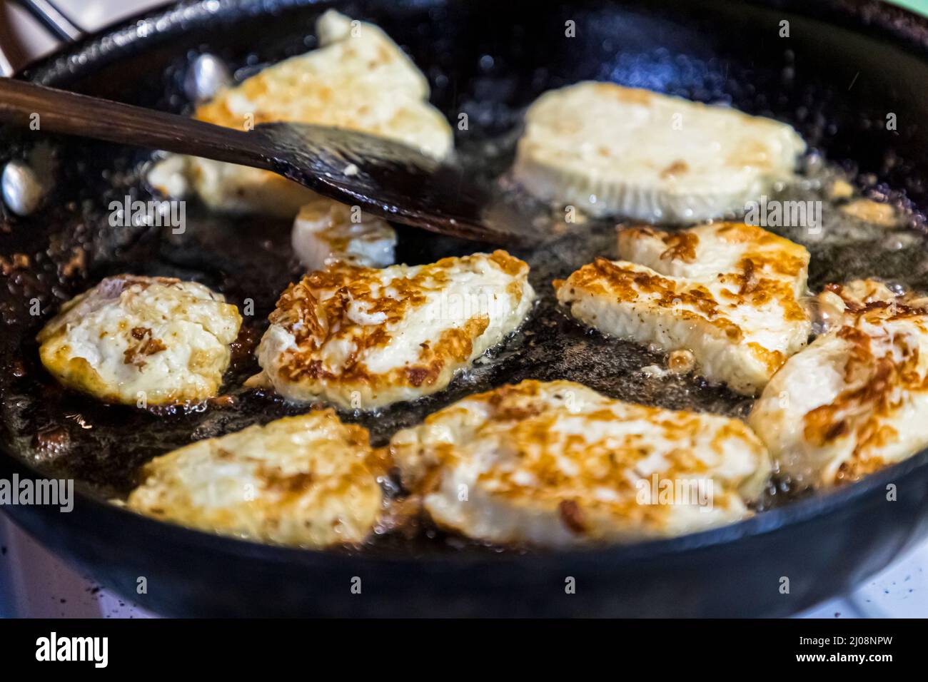 Halloumi wird in der Pfanne mit Sonnenblumenöl gebraten - es ist ziemlich stabil in Form und kann eine ganze Menge aushalten Stockfoto