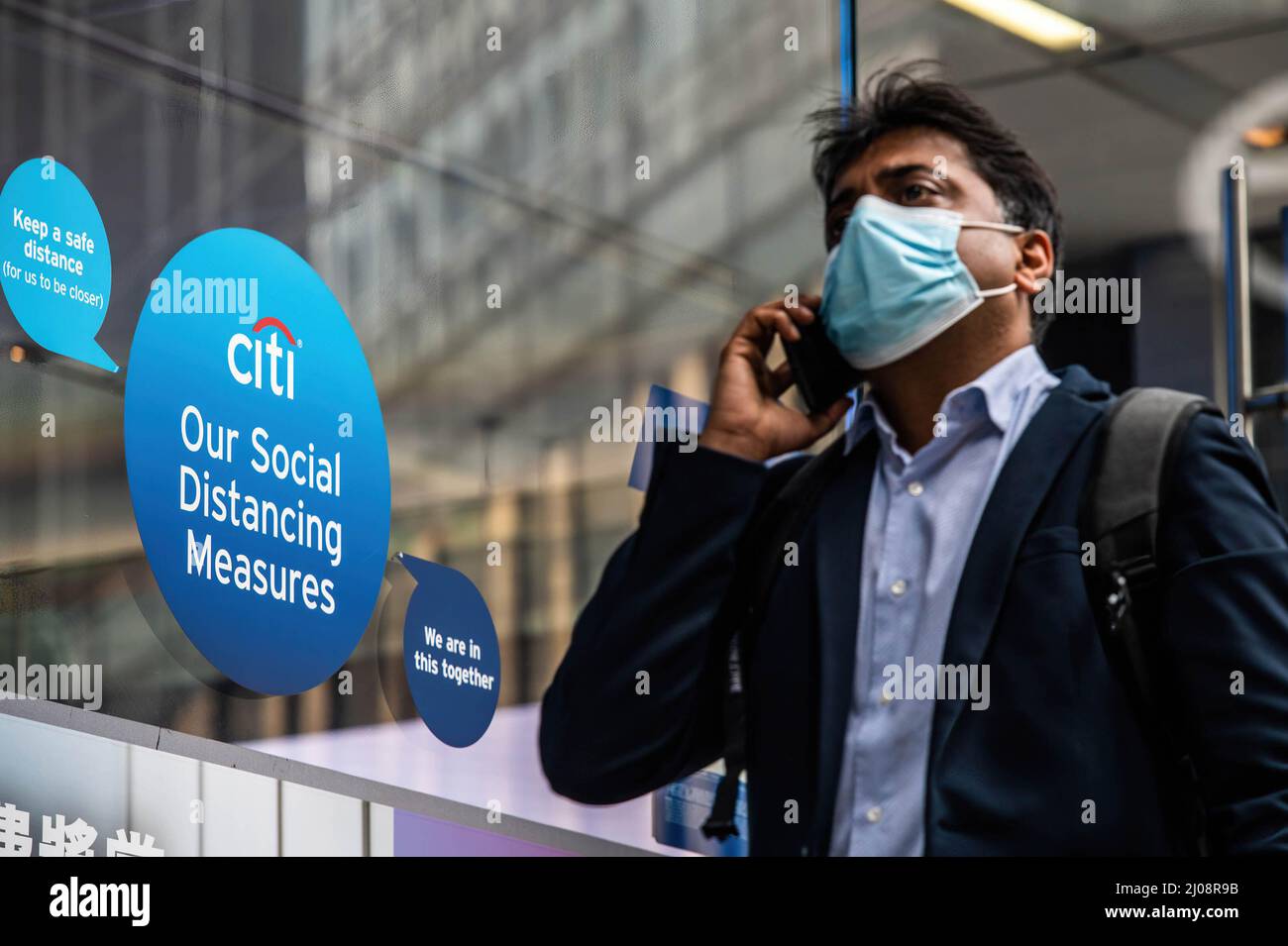 Ein Mann, der eine OP-Maske trägt, kommt an einem Outlet der Citi Bank im Central Business District von Hongkong vorbei. Nach der wirtschaftlichen Analyse der Regierung von Hongkong steht der Einzelhandel kurzfristig unter immensem Druck, da die Pandemie und die damit verbundenen sozialen Distanzierungsmaßnahmen eine Herausforderung für eine Wiederbelebung darstellen. Stockfoto