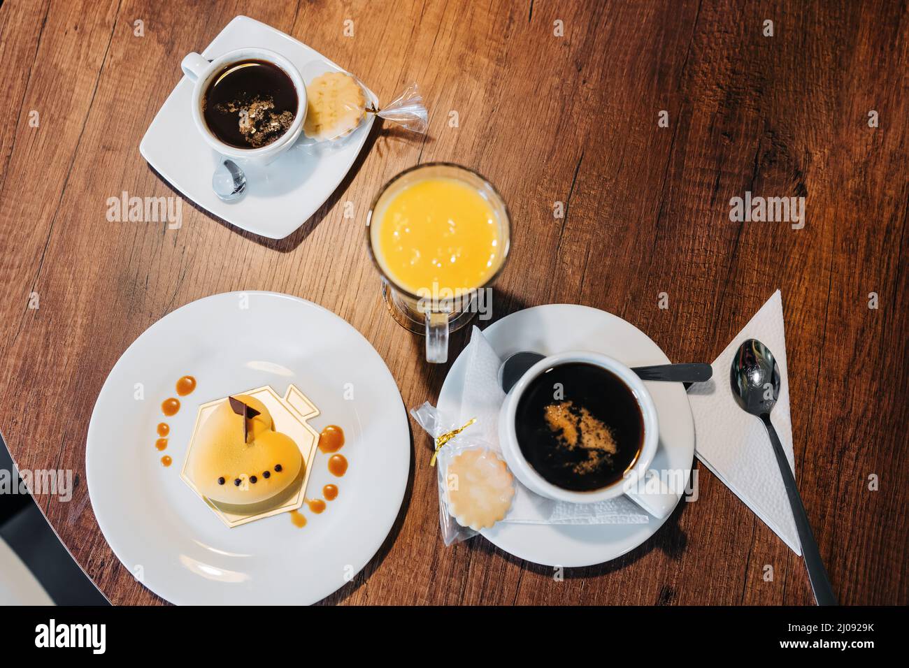 Top-Perspektive von Speisen und Getränken, Details von Kuchen mit Glasur dekoriert, eine Tasse Kaffee und ein Glas Orangensaft, Cafeteria im Restaurant Stockfoto