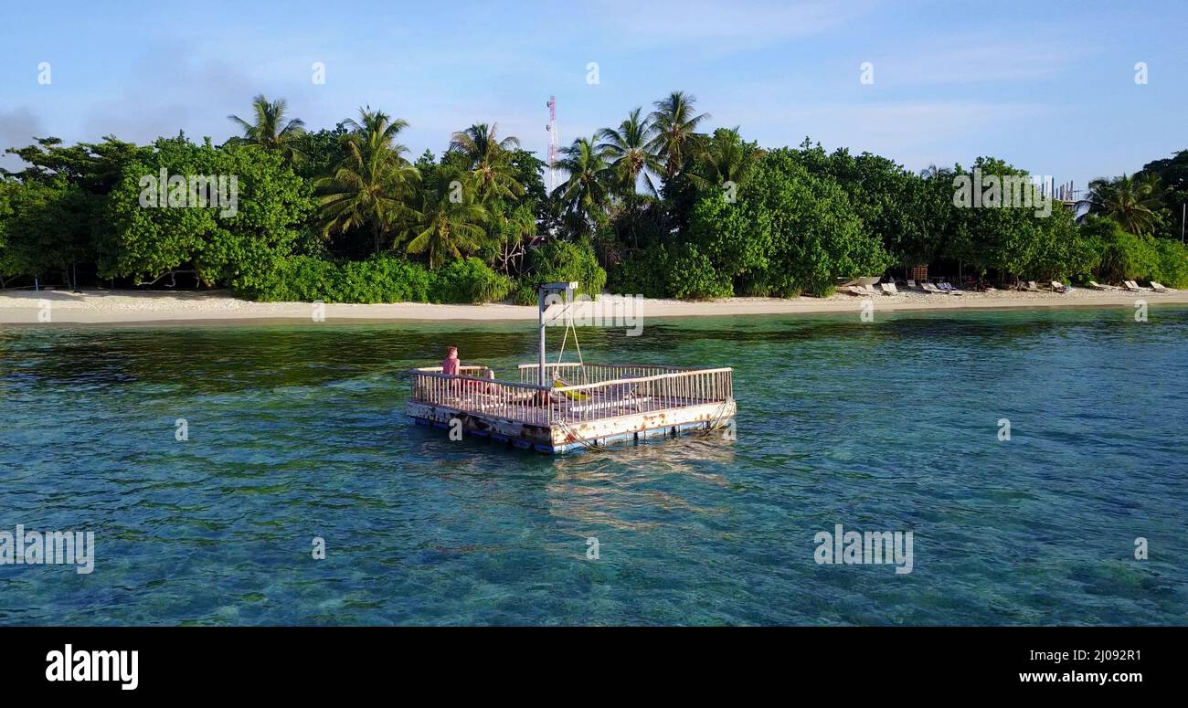 Blick auf einen schwimmenden Dock auf dem Meer mit einem Paar, das auf Rasdhoo Island, den Malediven, ruht Stockfoto