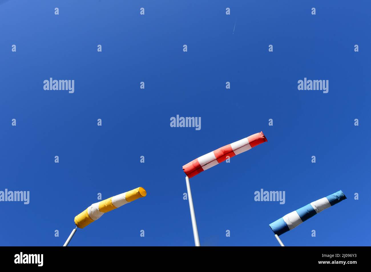 Drei Windsocken in Gelb, Rot und Blau mit weißen Streifen in der gleichen Richtung in klaren blauen Himmel korrigiert Stockfoto