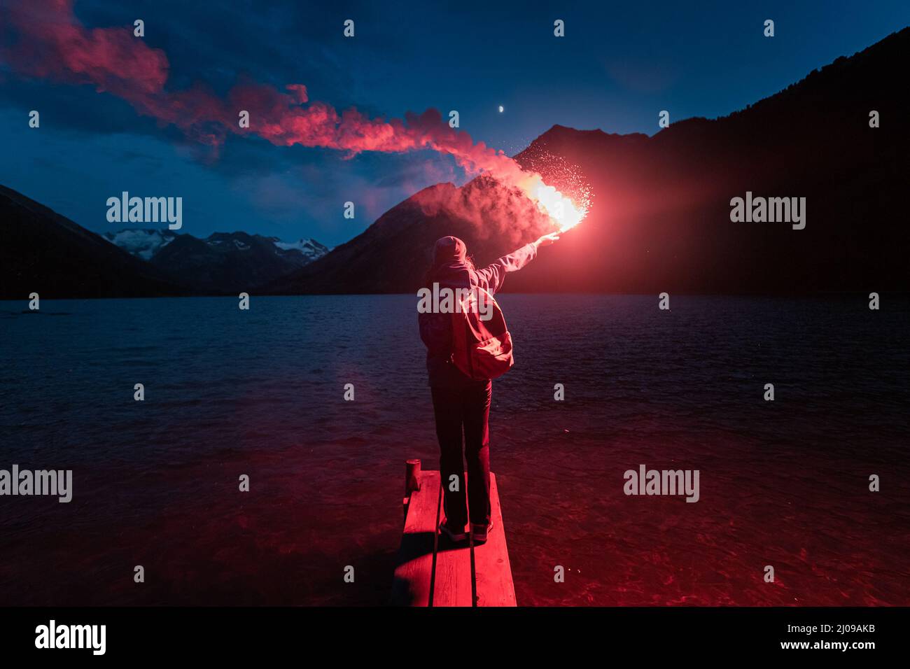 Der Wanderer auf dem Pier zündete die rote Notfackel an und rief um Hilfe. Rettungsflare und sos-Signalkonzept Stockfoto