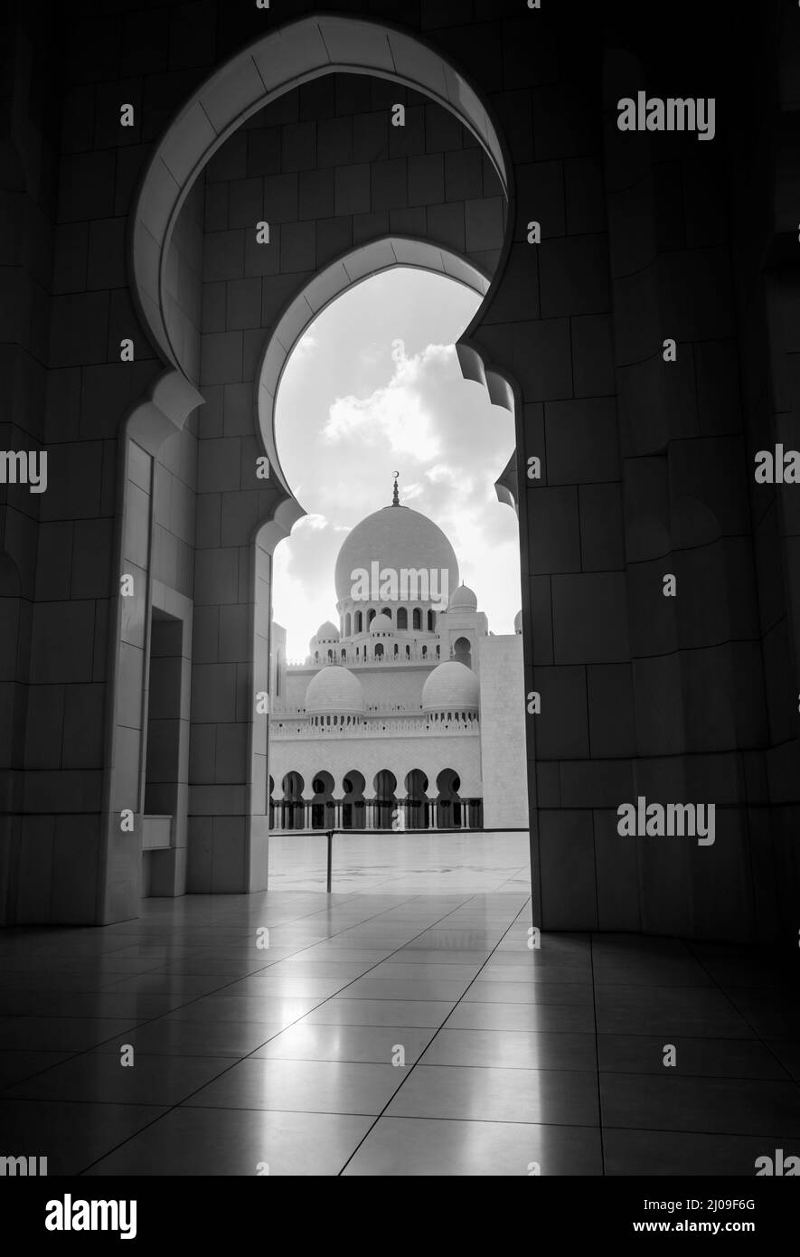 Ein Blick auf eine Kuppel der Scheich-Zayed-Moschee durch einen Bogen. Wunderschöne und prächtige Moschee aus Abu dhabi. Schwarzweiß-Foto Stockfoto