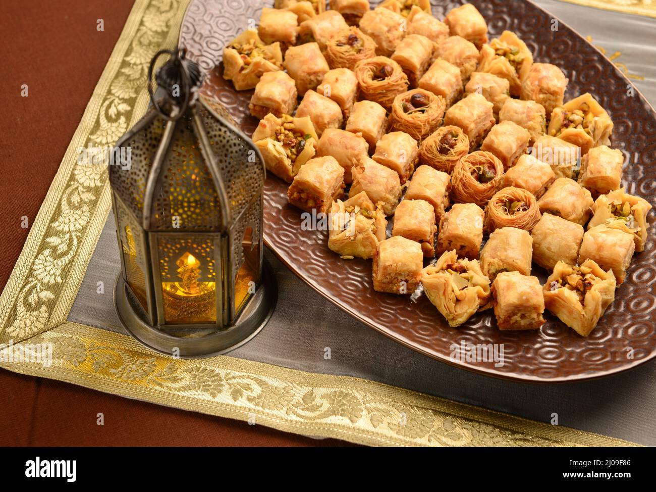 Festessen im Ramadan. Baklava serviert in einem großen Teller, zusammen mit einer traditionellen ägyptischen Laterne platziert. Stockfoto