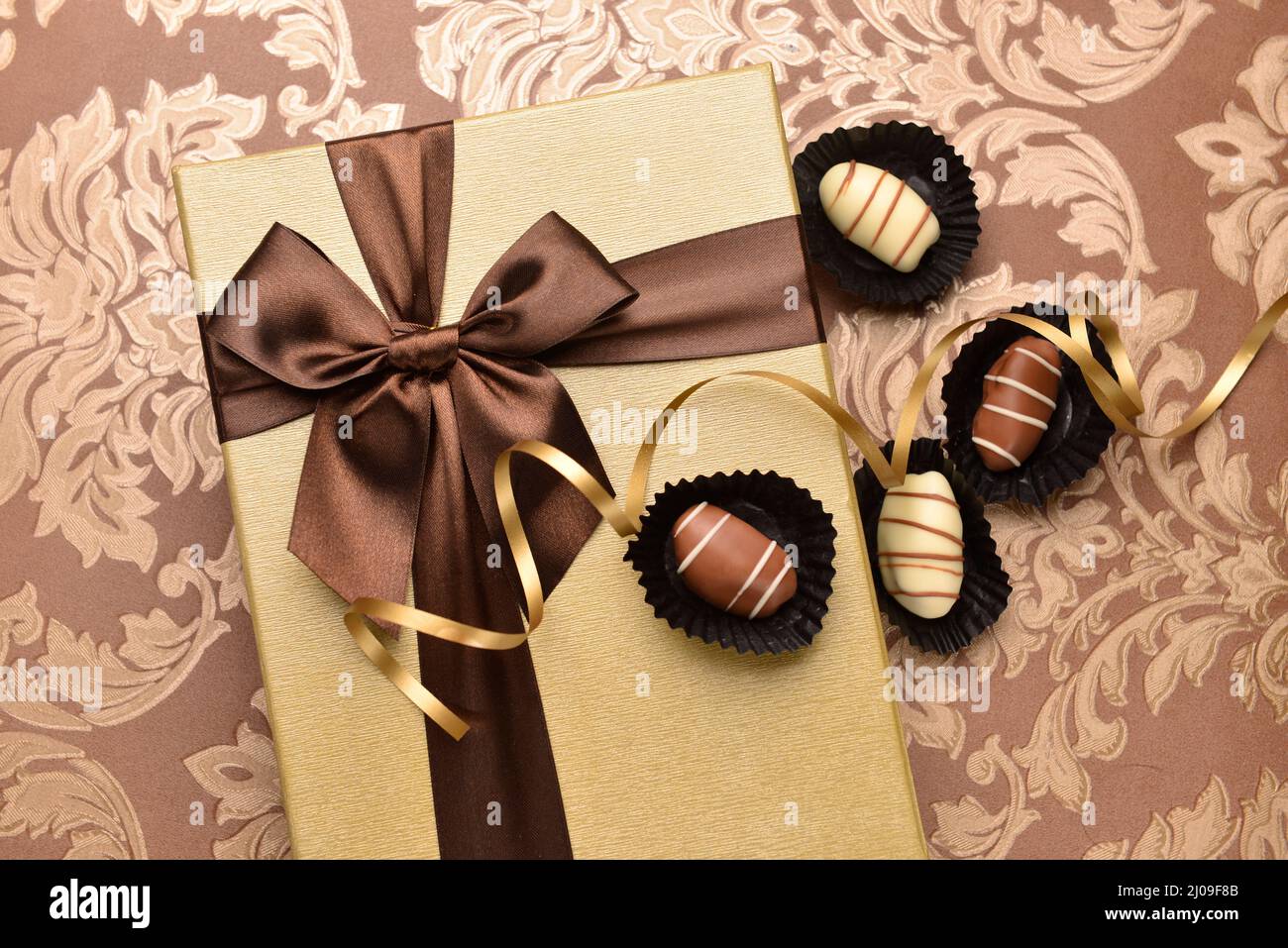 Premium-Dattel-Schokolade und geschlossene goldene Geschenkpackung mit Band. Draufsicht. Stockfoto
