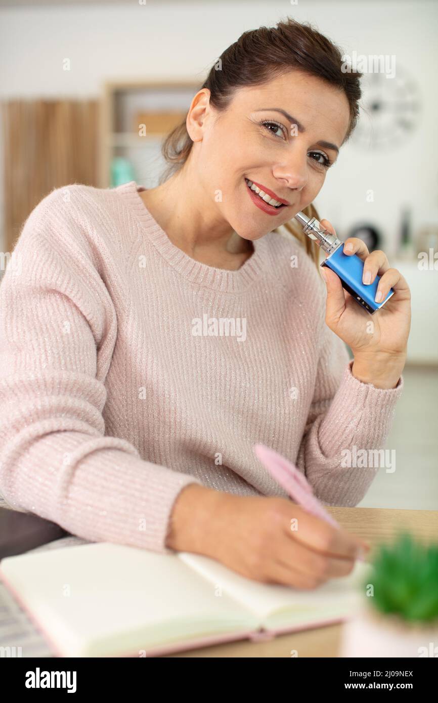 Frau mit elektronischem Zigarettenschreibjournal Stockfoto