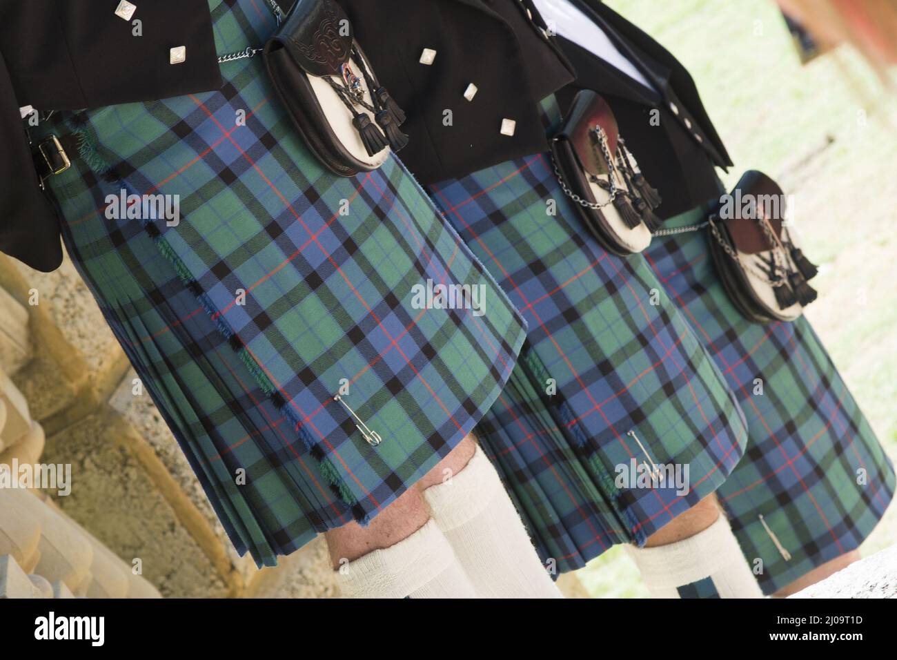 Nahaufnahme von drei Männerbeinen in schottischem Kilt, die nebeneinander stehen Stockfoto