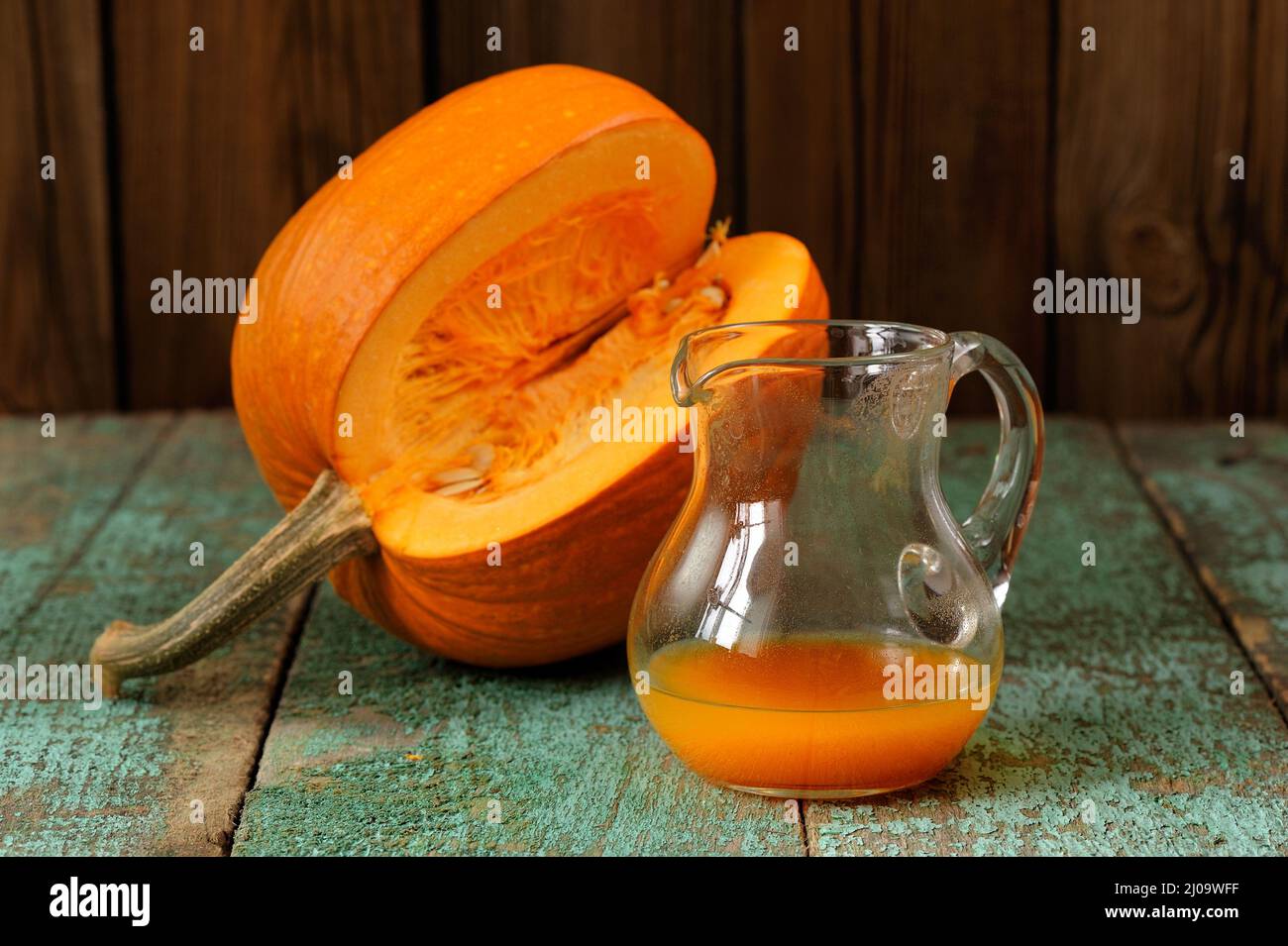 Kürbissaft im Glas und Kürbis mit Samen auf Holz türkisfarbenen Tisch ...