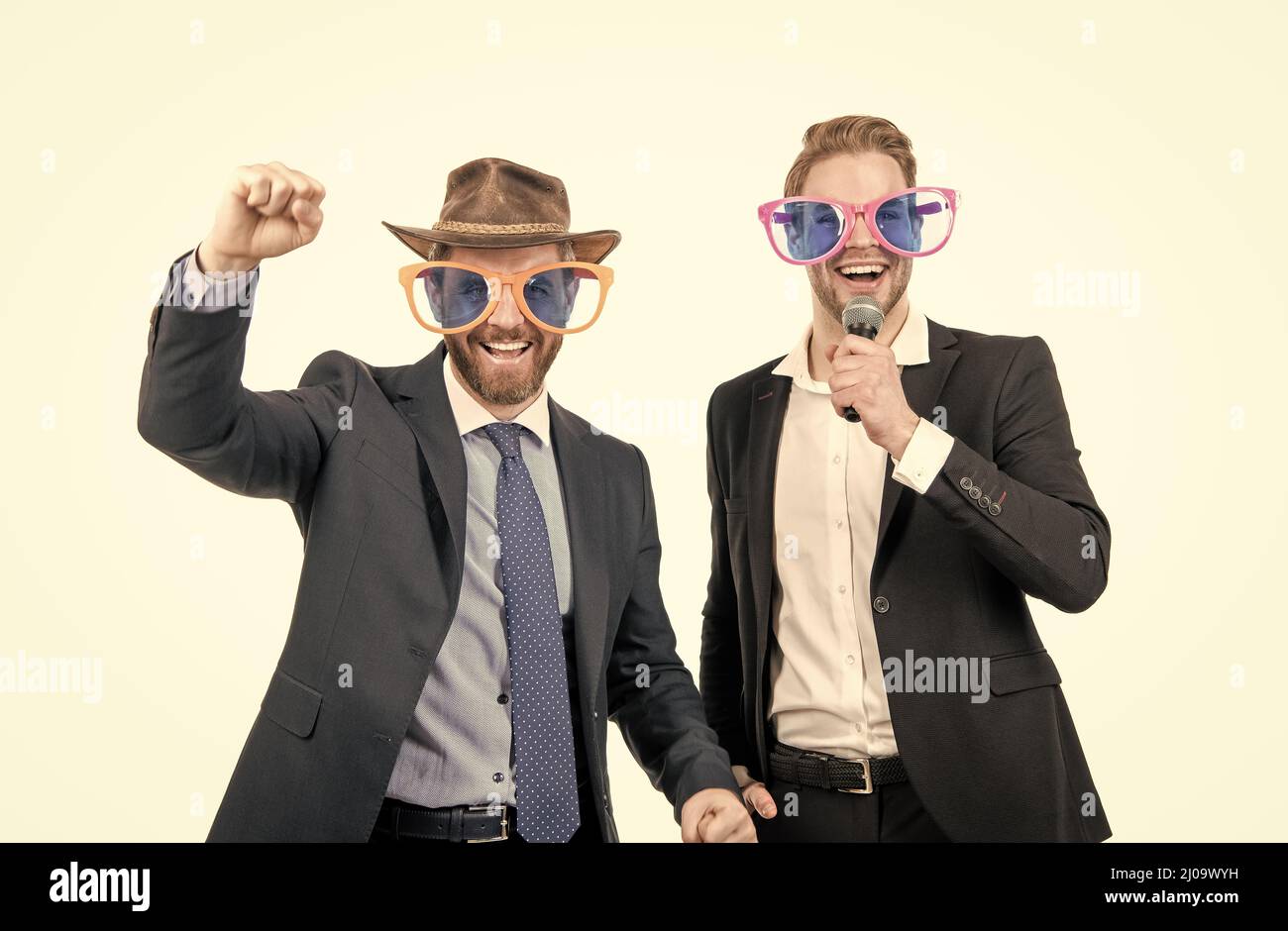 Glückliche Mitarbeiter haben Spaß, Karaoke in lustigen Brillen und formalwear singen, Firmenfeier Stockfoto