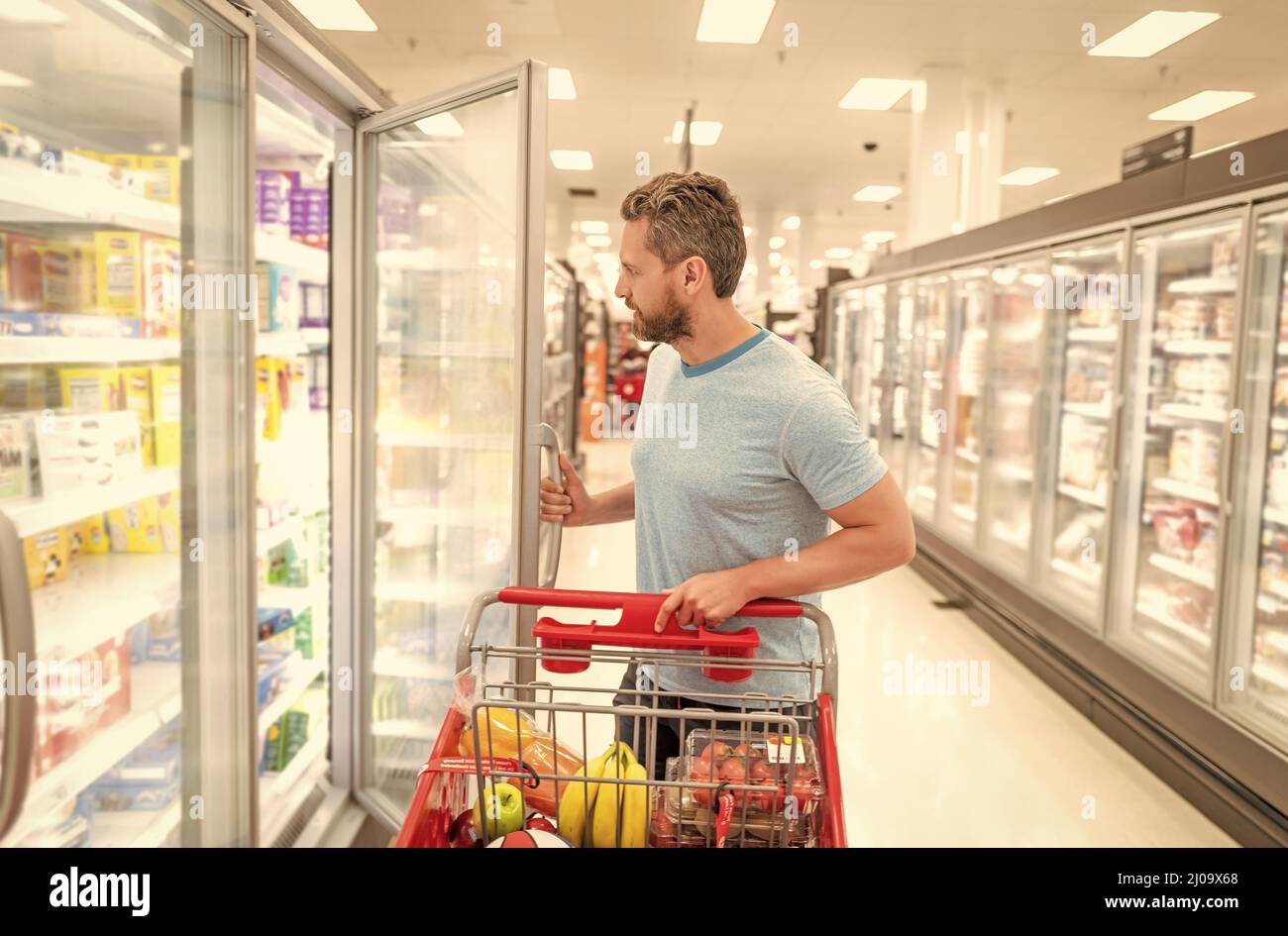 Mann mit Einkaufswagen Kauf von Lebensmitteln im Lebensmittelgeschäft, Verbrauch Stockfoto