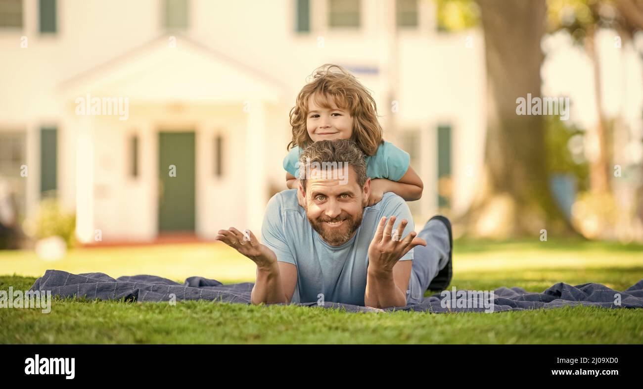 Lustige Vater mit Sohn entspannen zusammen auf grünen Park Gras, Freundschaft Stockfoto