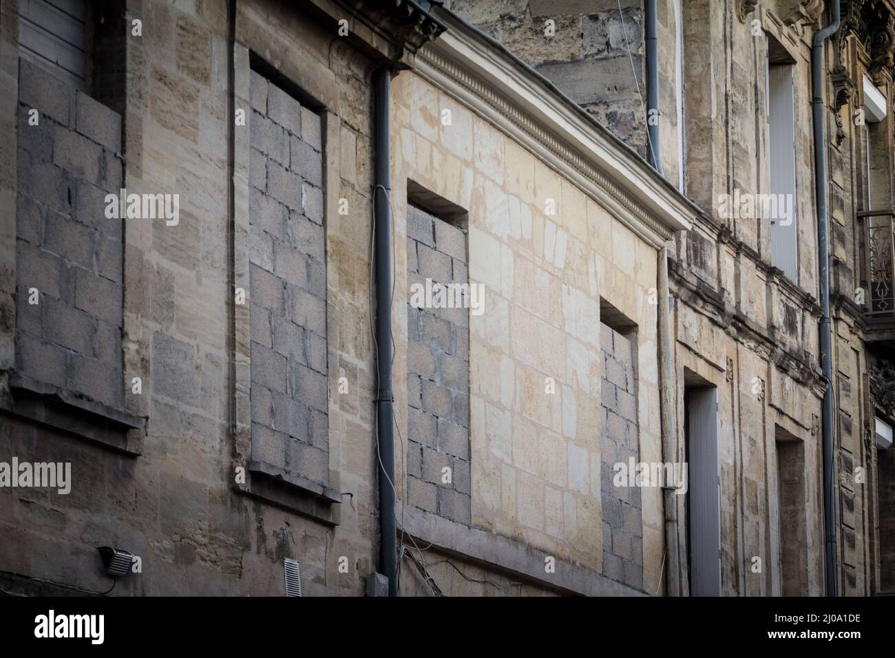 Selektive Verschwommenheit auf verurteilten, vertalten und zugemauerten Fenstern an einer Fassade eines alten Wohnhauses in einer Straße der Altstadt, historischem Zentrum Stockfoto