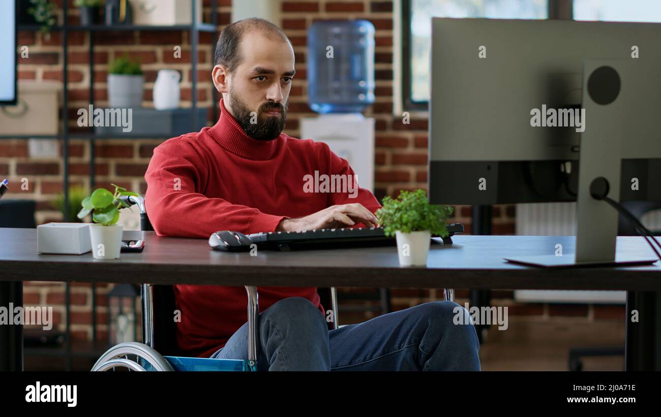 Junge Unternehmer, die Computer verwenden, um Datendiagramme zu erstellen, arbeiten in behinderungsfreundlichen Büros. Männliche Arbeitnehmer mit Behinderung Planung Marketing-Statistiken über Internet-Verbindung, Executive Job. Stockfoto
