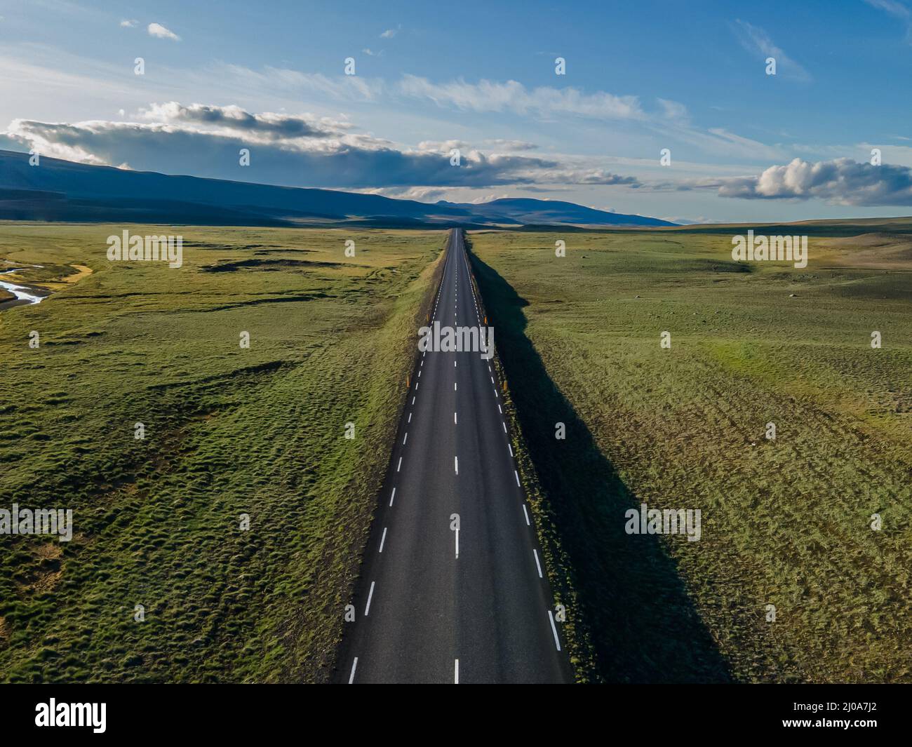 Schöne filmische Luftaufnahme der großen einsamen Autobahnen, die zwischen Bergen und Natur kreuzen, in Island Stockfoto