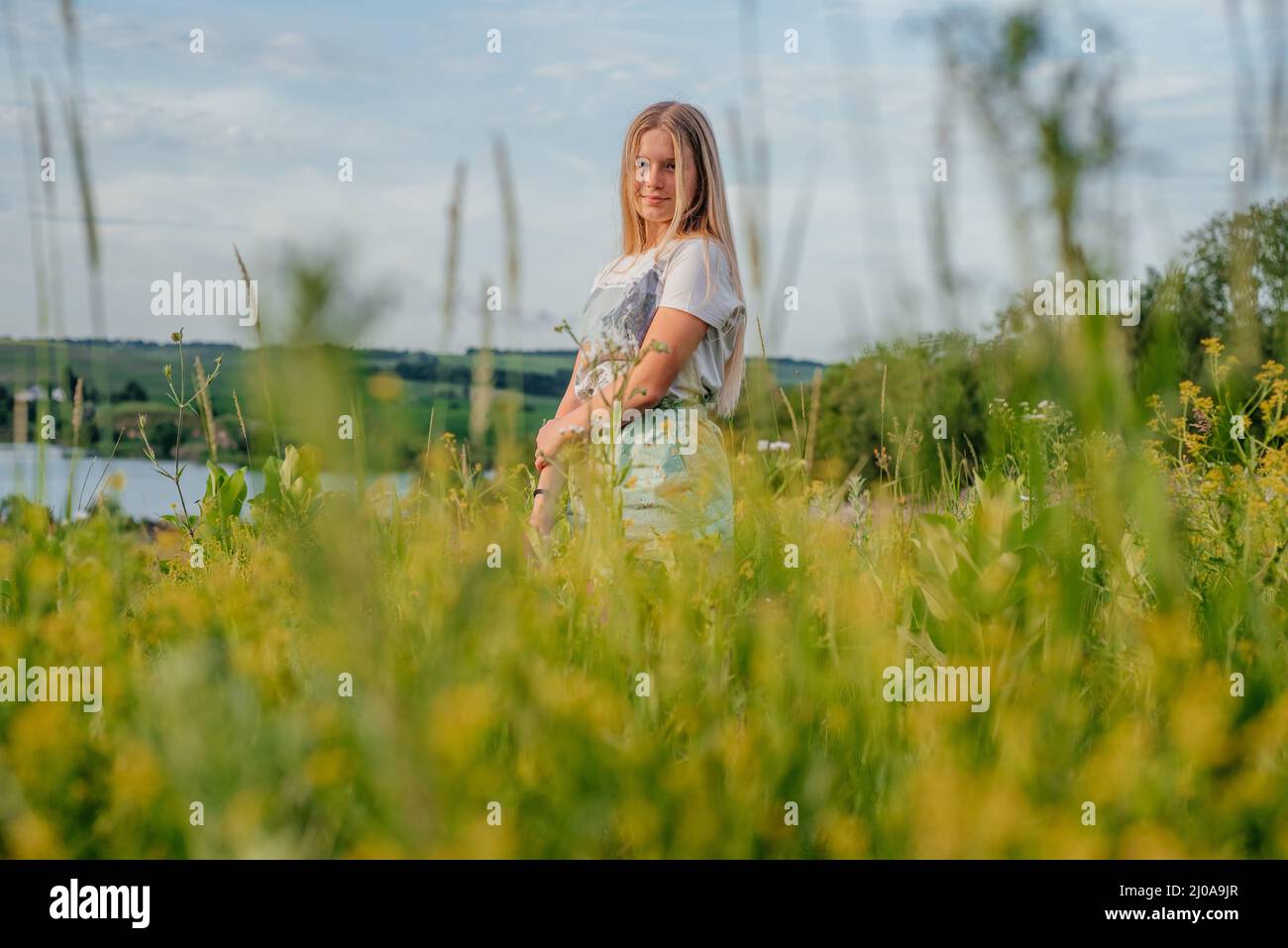 Ein schönes junges Mädchen unter gelben Blumen in der ländlichen Landschaft der Ukraine im Sommer Stockfoto
