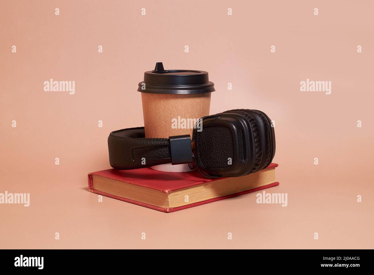 Hörbuch. Eine Papptasse Kaffee und Kopfhörer liegen auf einem Buch Stockfoto