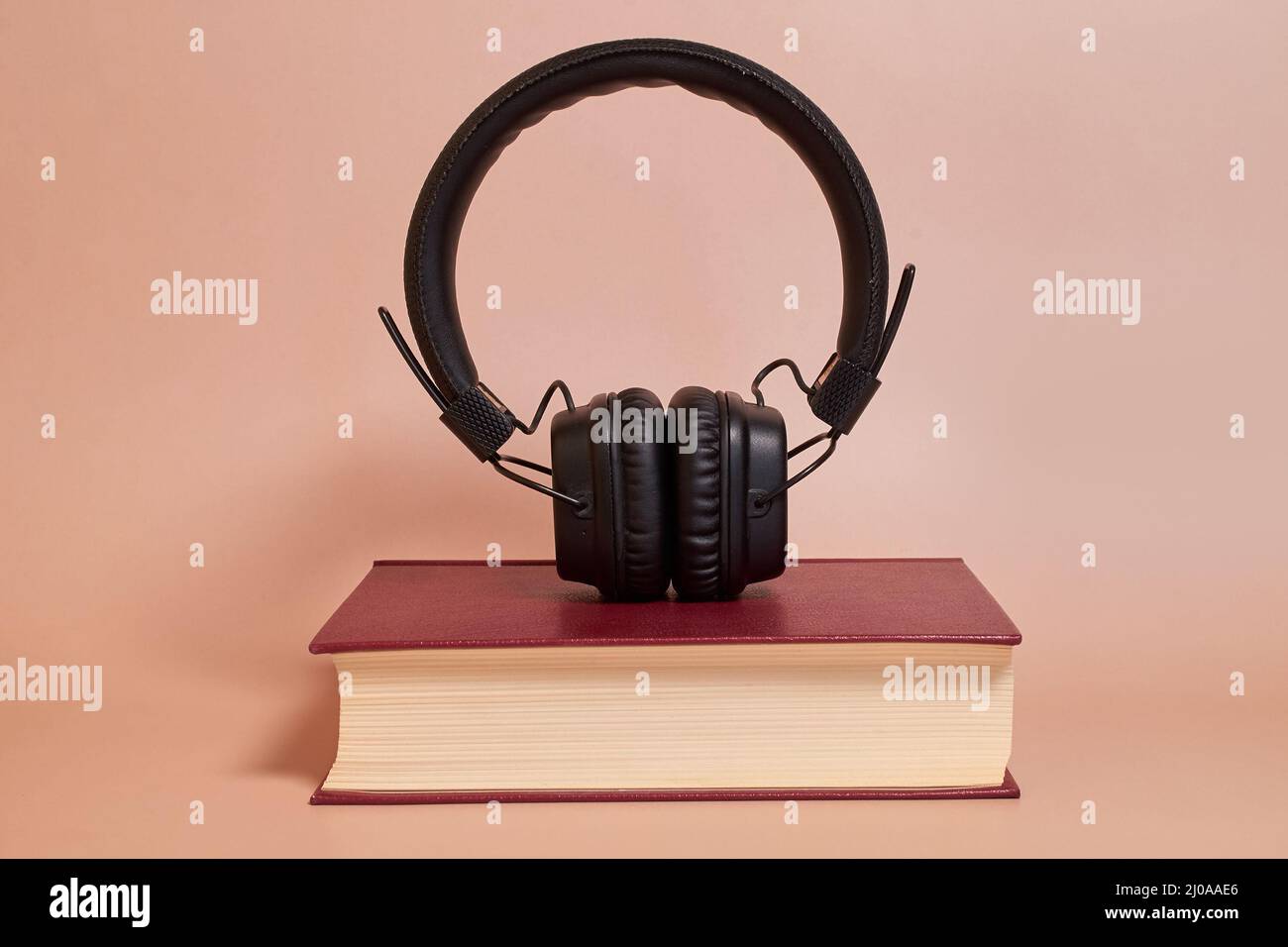 Hörbuch. Die Kopfhörer stehen auf einem Buch auf einem farbigen Hintergrund Stockfoto
