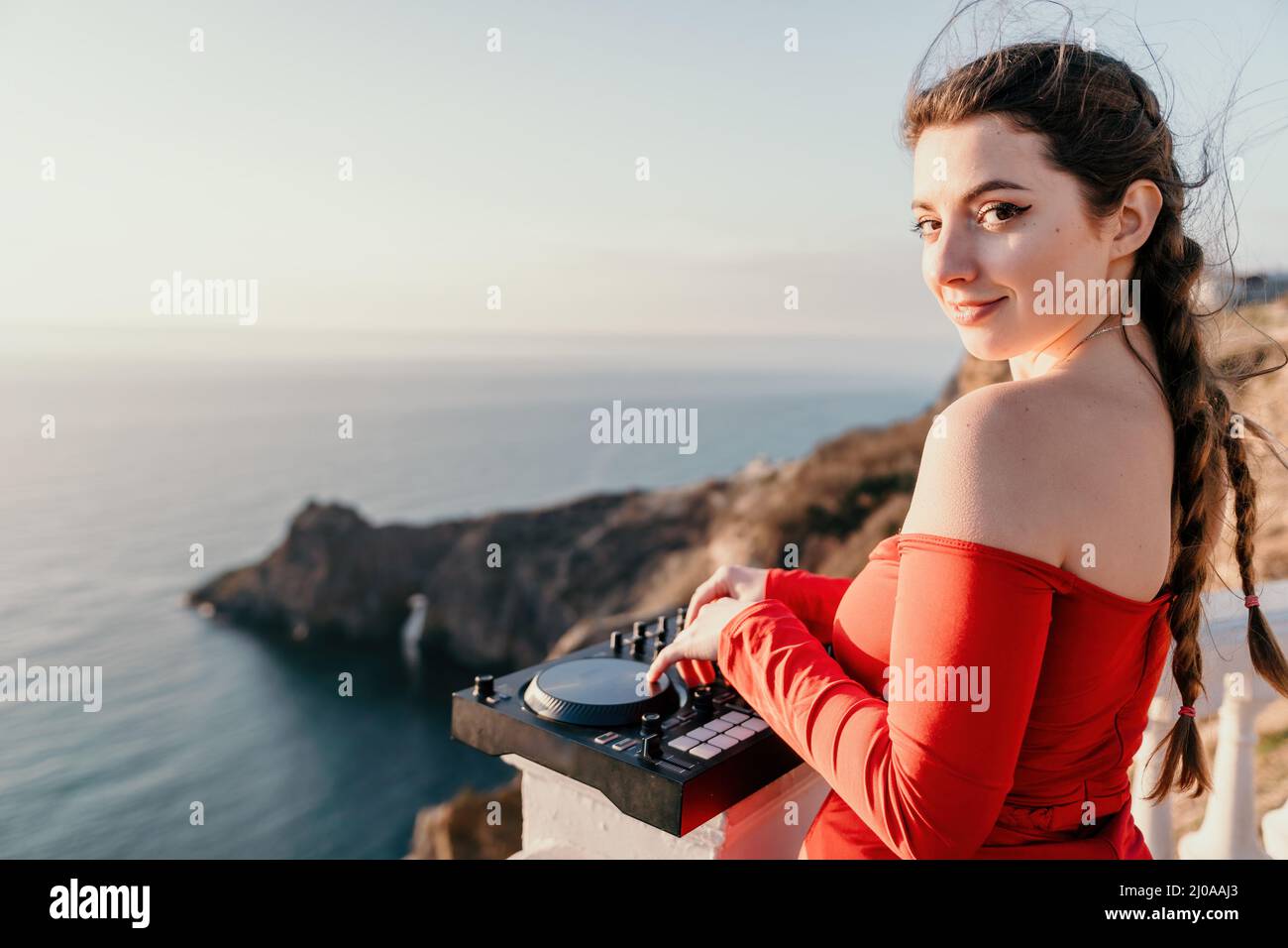 Weibliche Hände von DJ spielen Musik mischen und kratzen auf Abendparty mit Meereshintergrund und weichen warmen Sonnenuntergang. Nahaufnahme einer DJ-Konsole, die von gesteuert wird Stockfoto