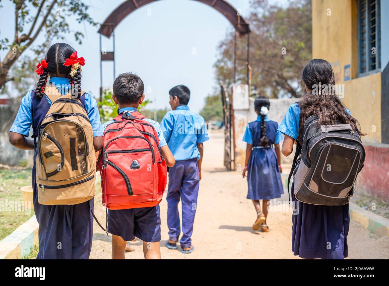 Rückansicht Aufnahme einer Gruppe von Jugendlichen Kindern in Unifrom, die nach dem Unterricht von der Schule nach Hause gehen - Konzept von Bildung, Lernen und Wachstum der Kindheit Stockfoto