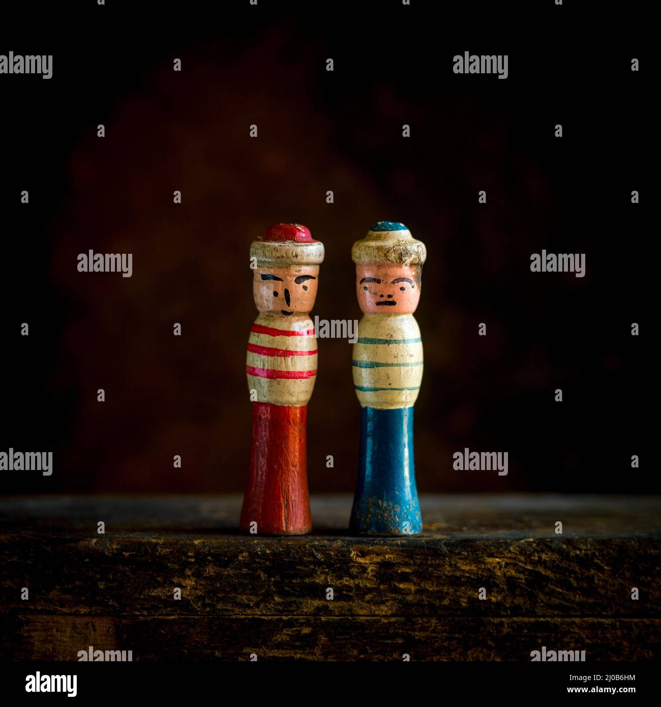 Vintage-Holzfiguren stehen nebeneinander in einer schwach beleuchteten Umgebung Stockfoto