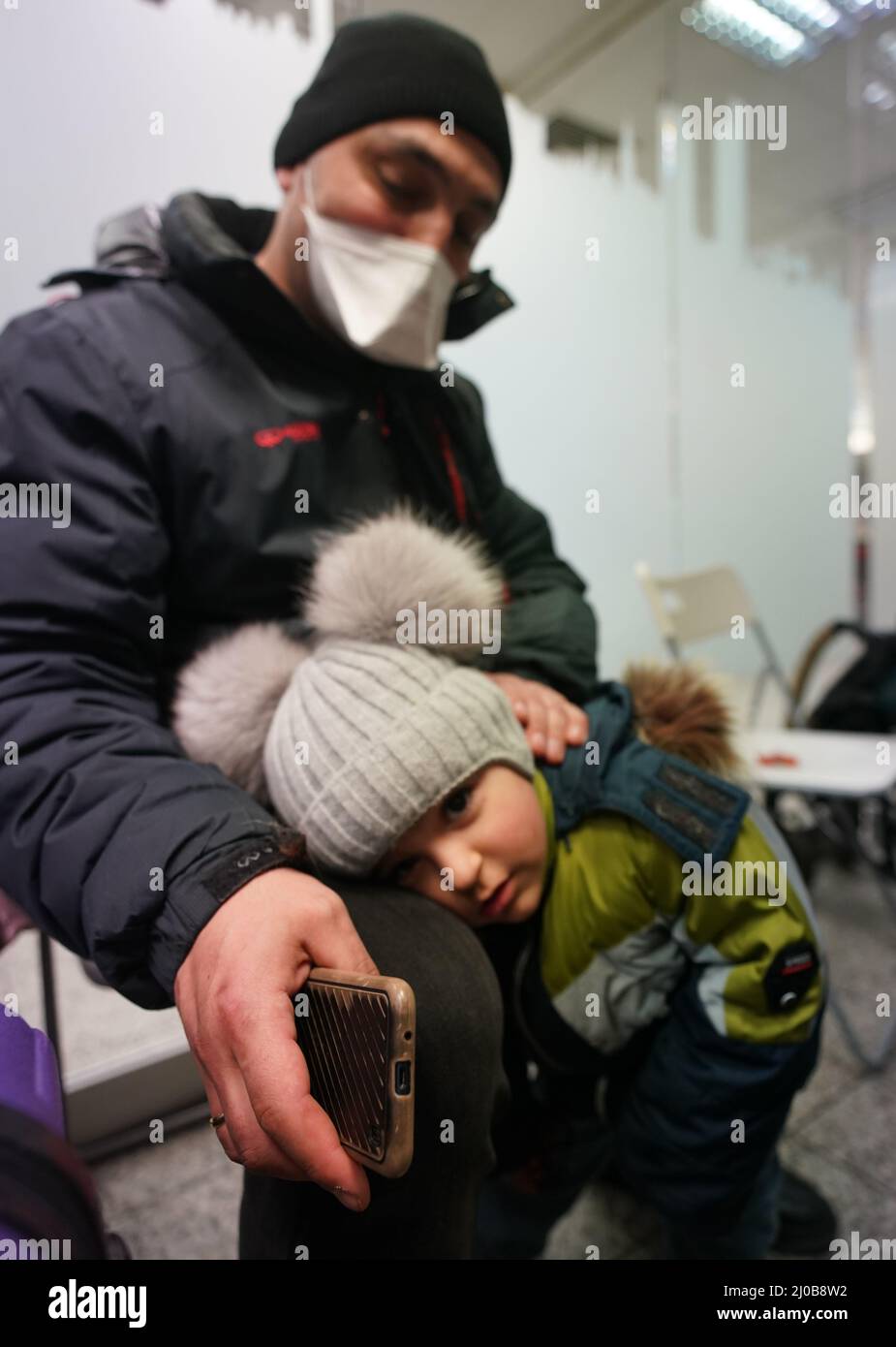 Hamburg, Deutschland. 18. März 2022. Der dreijährige Levon und sein Vater Edgar, Flüchtlinge aus der ukrainischen Stadt Poltawa, sitzen in einem Zimmer im Arbeiter-Samariter-Bund (ASB) im Hauptbahnhof. ASB-Mitarbeiter und Freiwillige sowie Übersetzer begrüßen die ukrainischen Flüchtlinge bei ihrer Ankunft am Hamburger Hauptbahnhof. Den Flüchtlingen werden Getränke und Essen sowie Informationen zur Anmeldung, zur freien Unterkunft oder Weiterreise zur Verfügung gestellt. Kredit: Marcus Brandt/dpa/Alamy Live Nachrichten Stockfoto