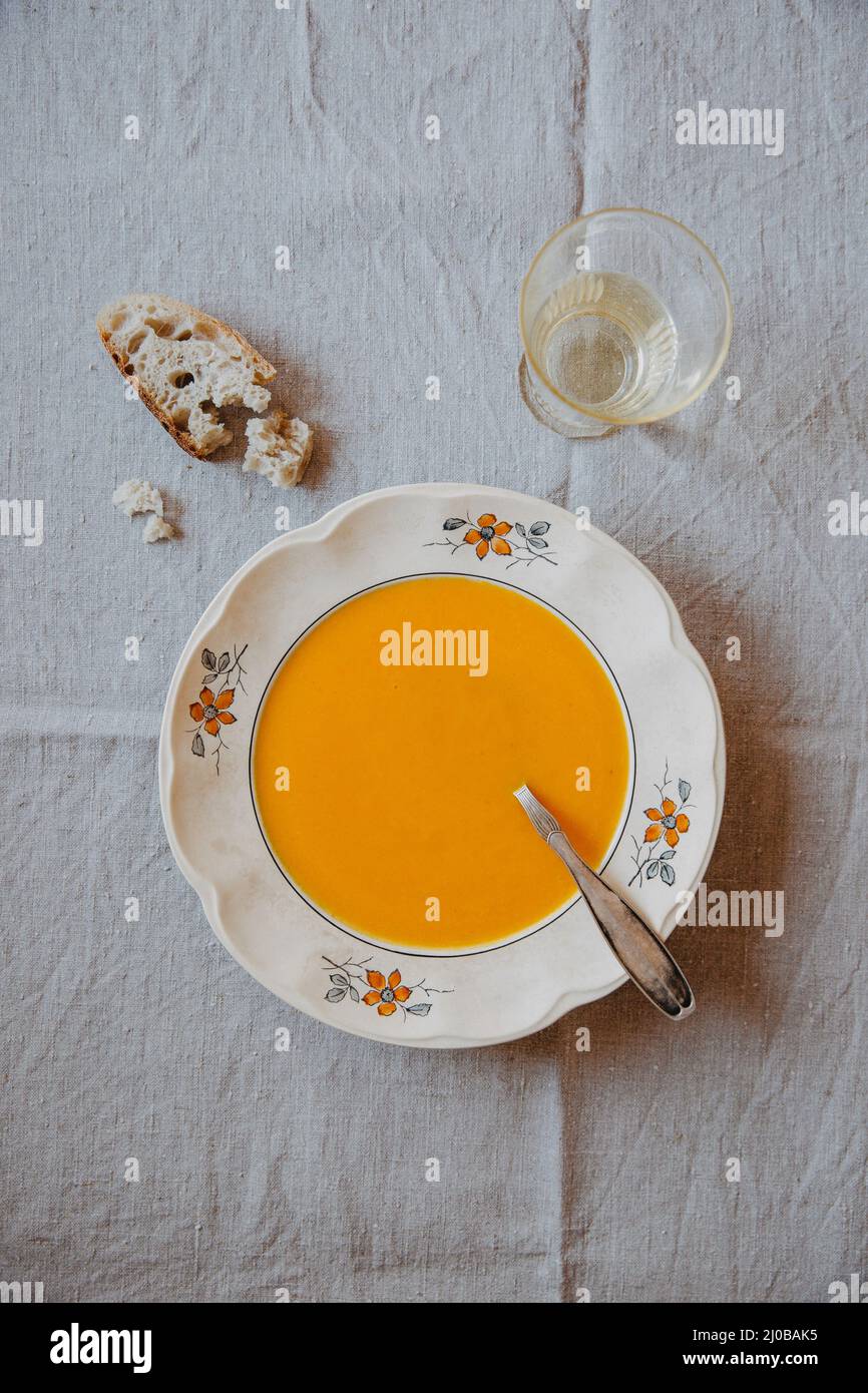 Eine Schüssel Karottensuppe auf einer beigefarbenen Leinentischdecke Stockfoto