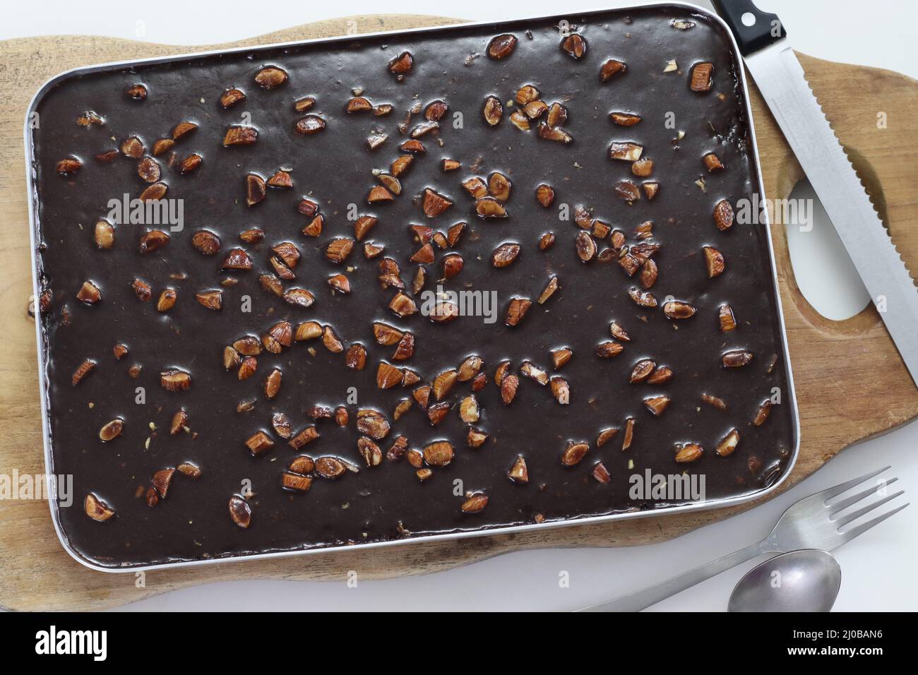 Texanischer Tortenbogen. Butterhaltiger und schokoladiger Kuchen im Backblech. Frisch aus dem Ofen. Aufgenommen auf weißem Hintergrund Stockfoto