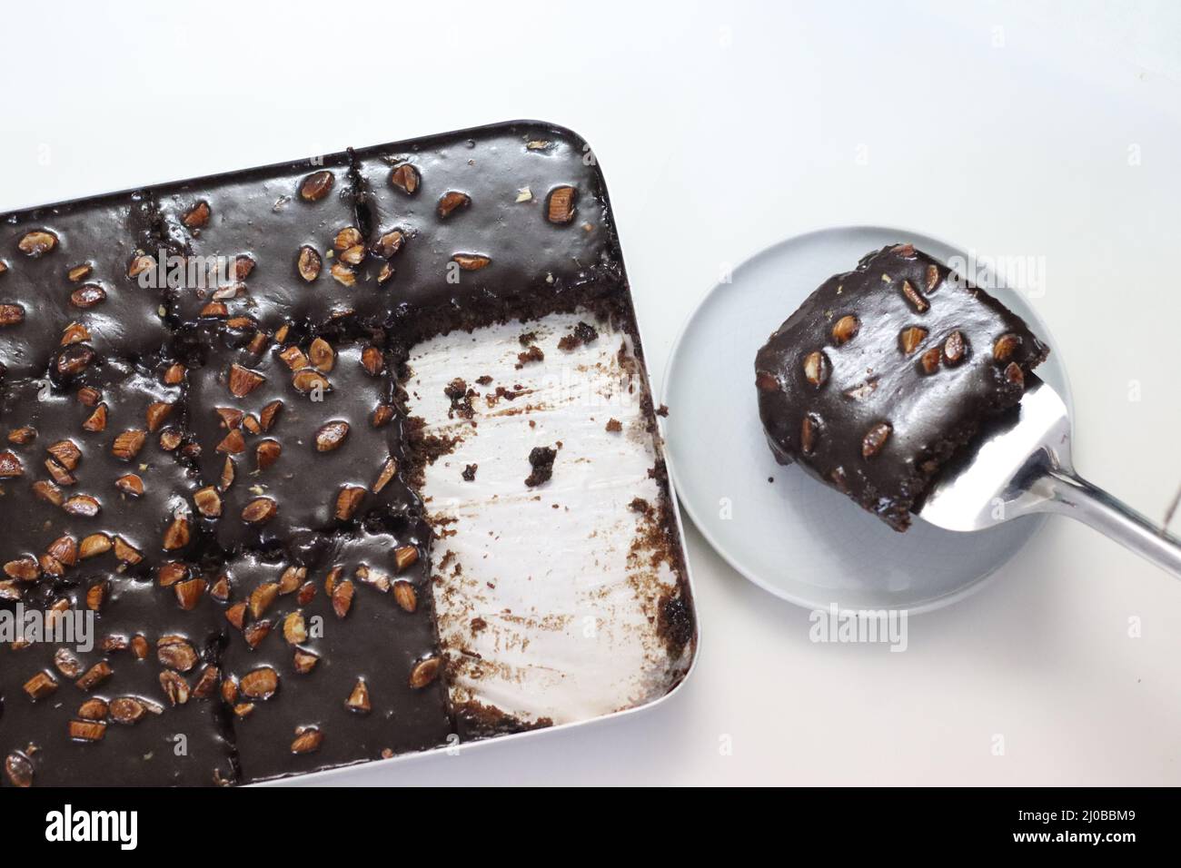 Ein Stück Texas-Torte auf einem Teller serviert. Butterhaltiger und schokoladiger Kuchen in rechteckige Stücke im Backblech geschnitten und daraus geschöpft. Aufnahme o Stockfoto