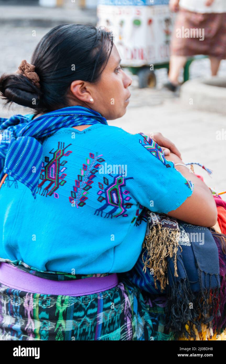 Einheimische Frau mit schwarzen Haaren in blauer Kleidung verkaufen Schals auf der Straße sitzen Stockfoto