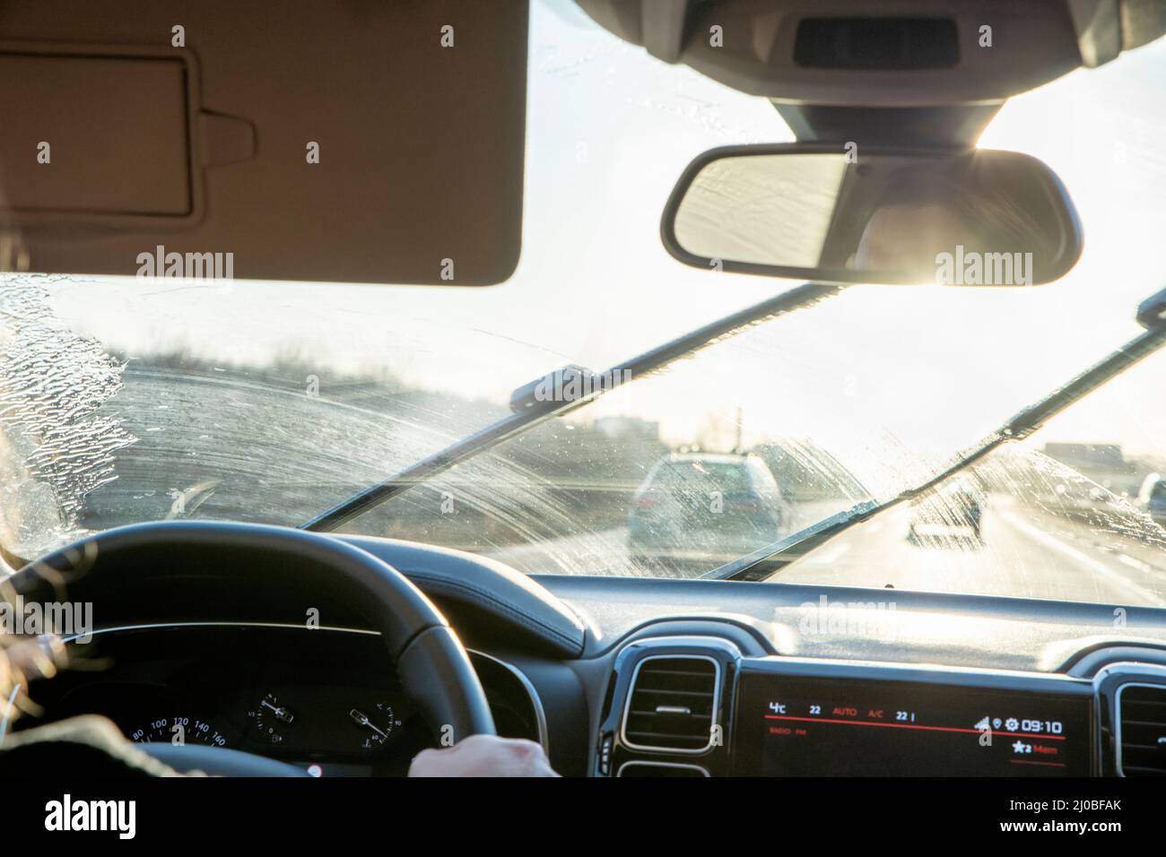 Im Auto auf der Autobahn mit Hintergrundbeleuchtung und schmutziger Windschutzscheibe Stockfoto