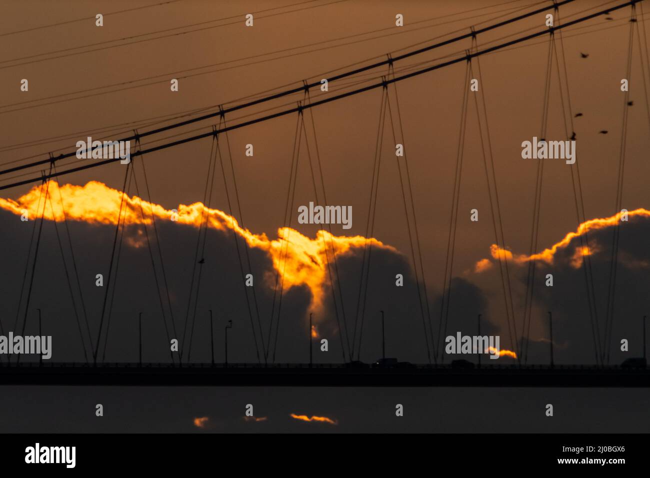 Littleton-upon-Severn, South Gloucestershire, England, Großbritannien. 10.. Februar 2022. Fahrzeuge werden als dramatische U-Bahnfahrt über die Severn-Brücke von M48 silhouettiert Stockfoto