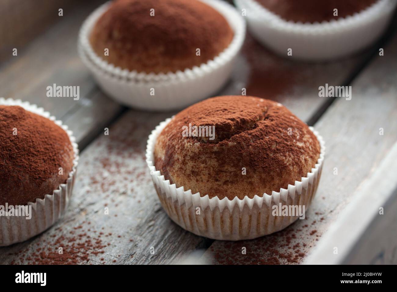 Muffins mit Dinkelmehl und Kakao in einer Holzkiste auf einem Tisch Stockfoto