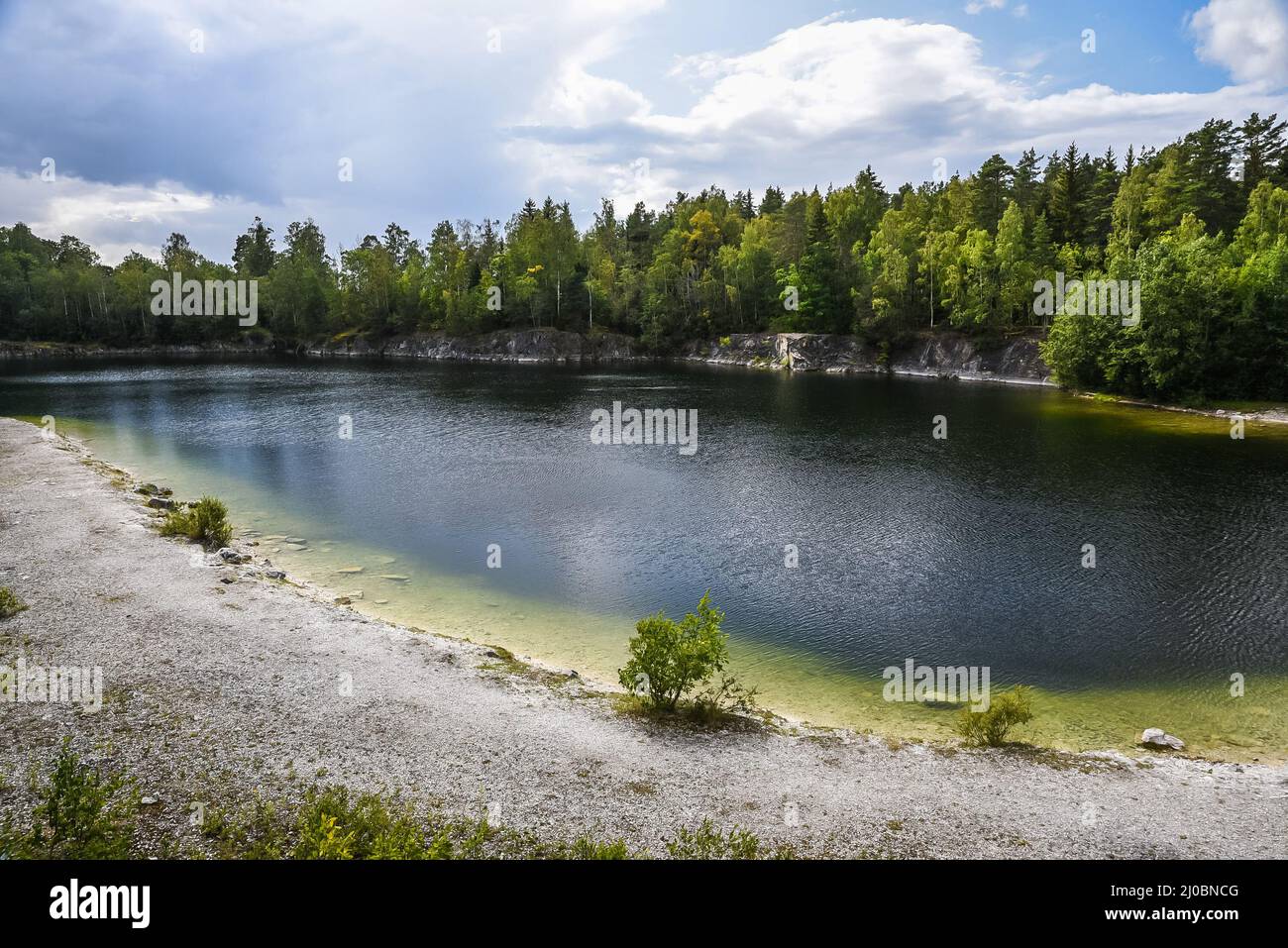 Panoramablick über den kleinen See und die natürliche Umgebung mit einem Strand und Wäldern rund um die Sala Silvergruva, die Sala Silver Mine, Schweden Stockfoto