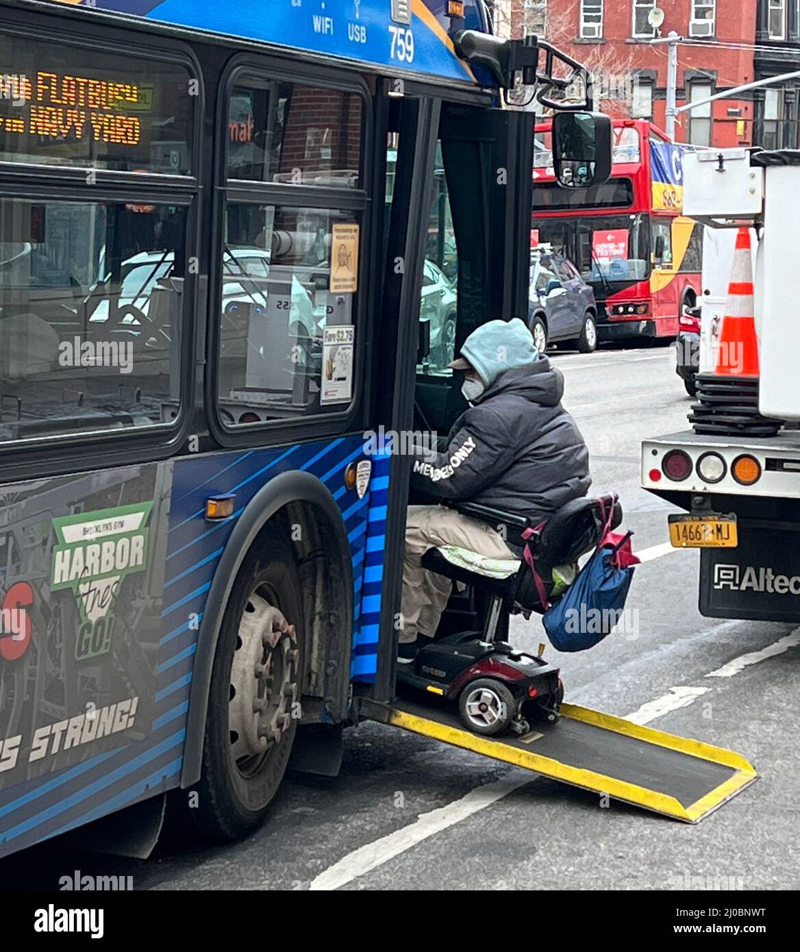 Behinderter Mann in einem Rollstuhl geht in einen Bus auf der 7. Avenue in Brooklyn, Newe York. Stockfoto