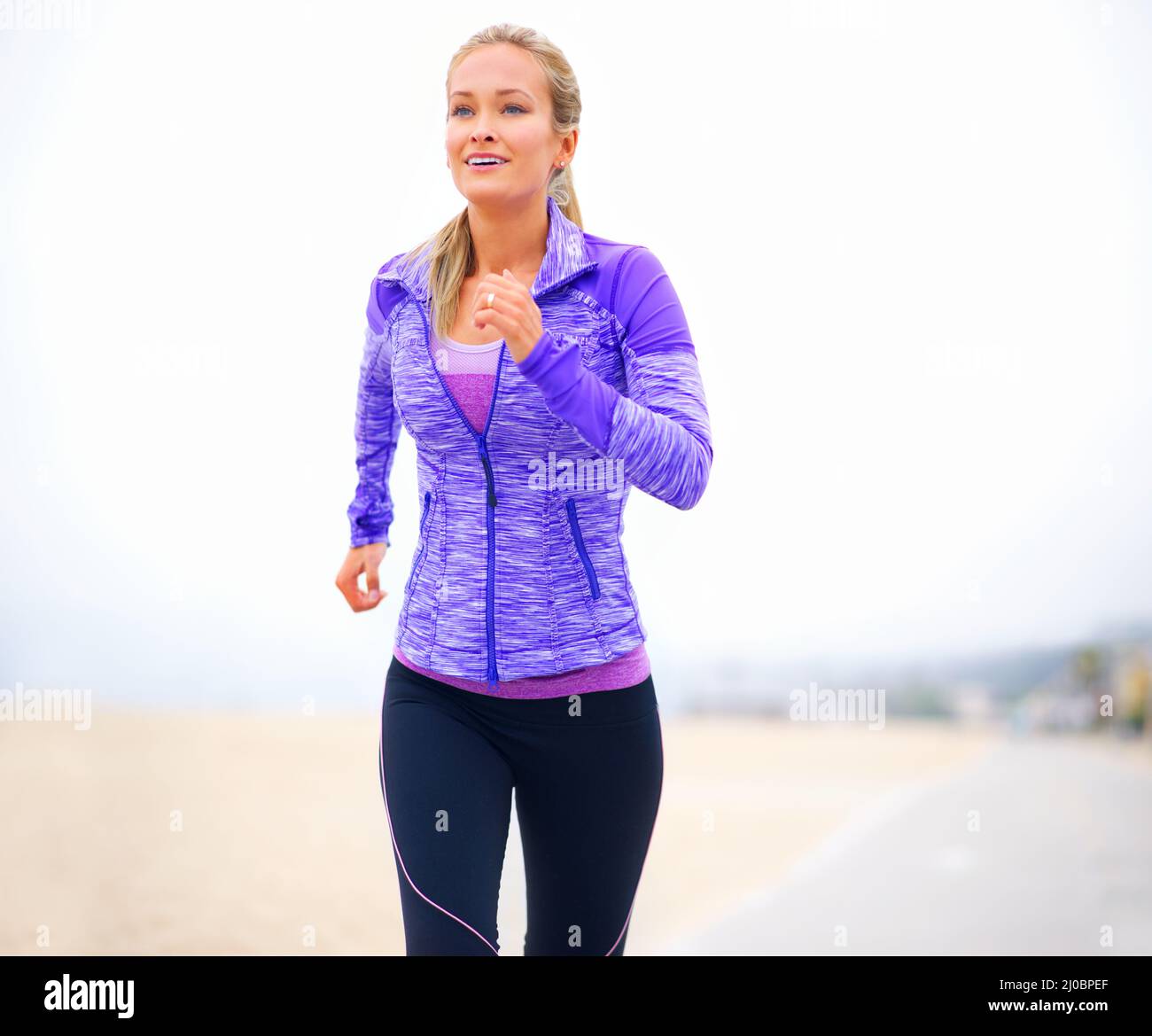 Fitter durch den Schritt. Aufnahme einer jungen Frau in Sportkleidung, die am Strand steht. Stockfoto