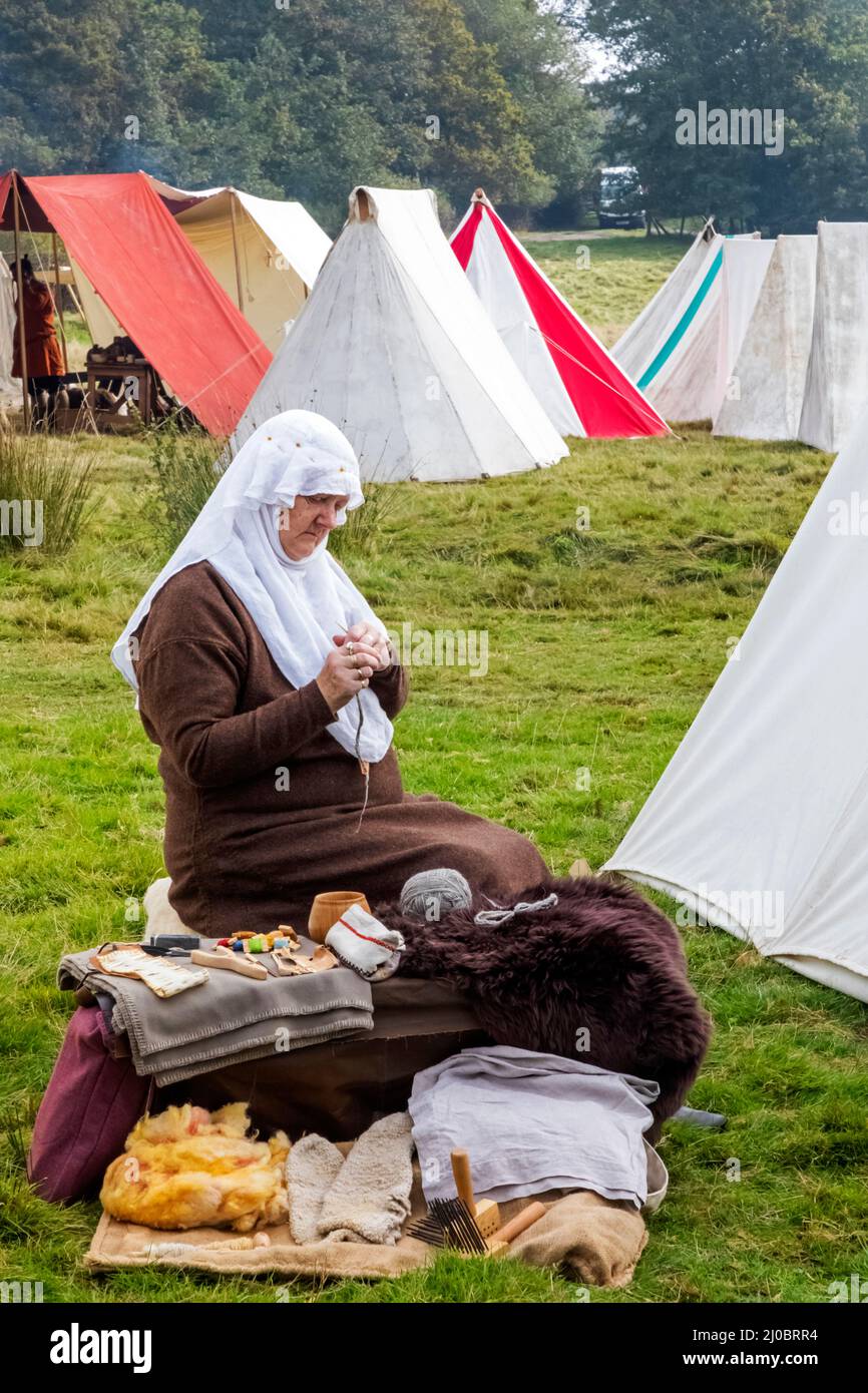England, East Sussex, Battle, The Annual Battle of Hastings 1066 Re-enactment Festival, Teilnehmerin im mittelalterlichen Kostüm Spinning Wool Stockfoto
