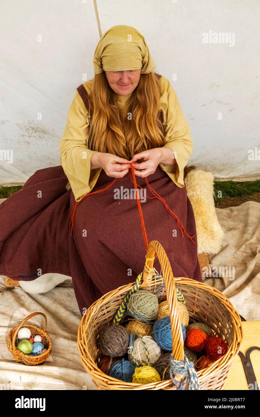 England, East Sussex, Battle, The Annual Battle of Hastings 1066 Re-enactment Festival, Teilnehmerin im mittelalterlichen Kostüm Spinning Wool Stockfoto